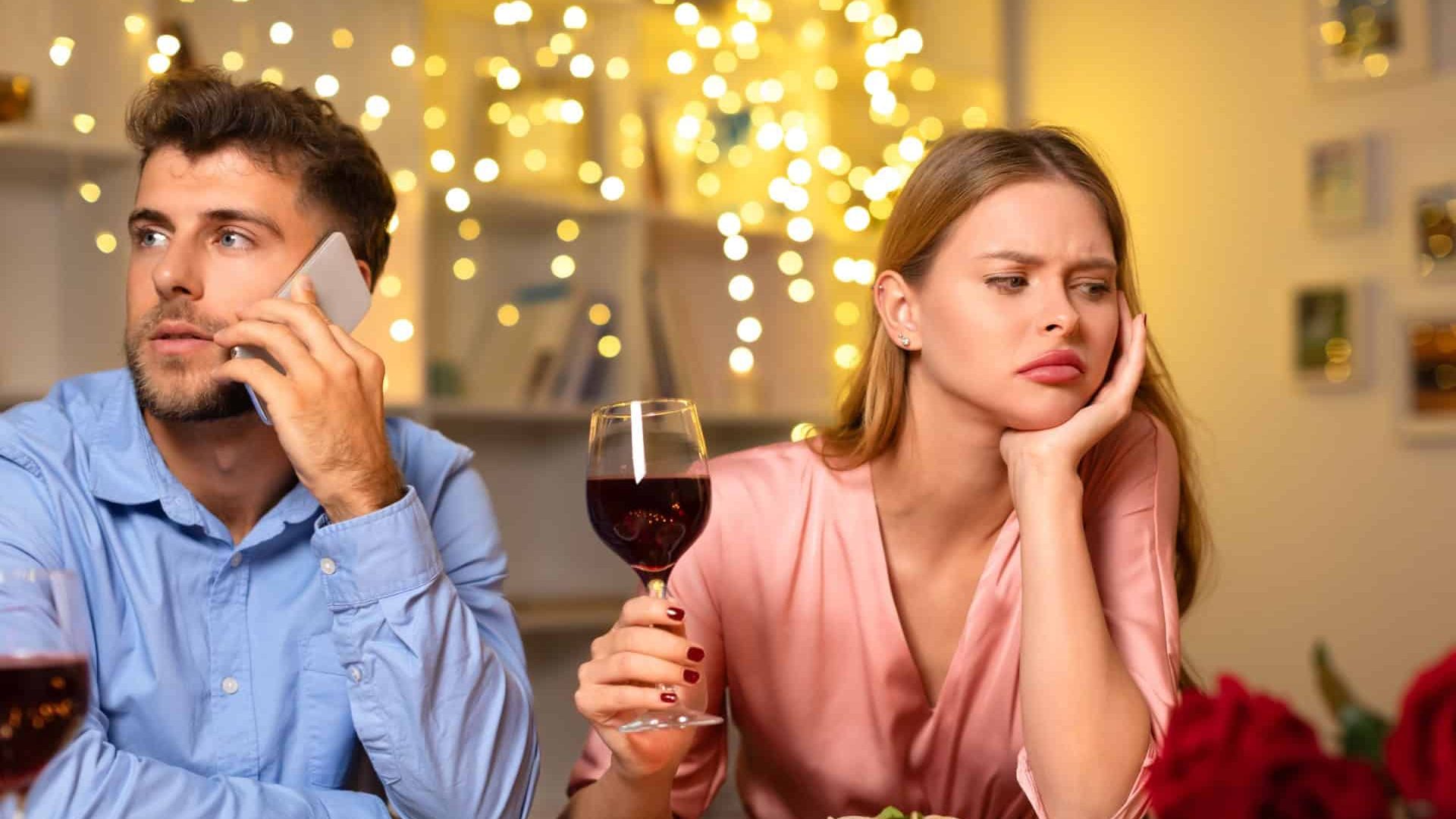 Man on call ignoring his date, leaving the woman feeling bored and disappointed during a romantic dinner with wine and pasta, atmosphere ruined
