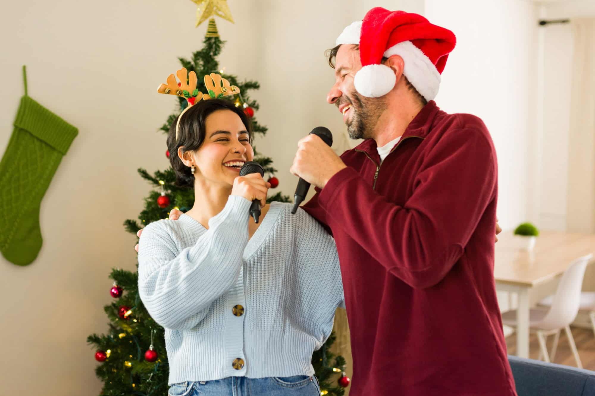 Happy couple is singing christmas carols together, having fun during christmas holidays at home