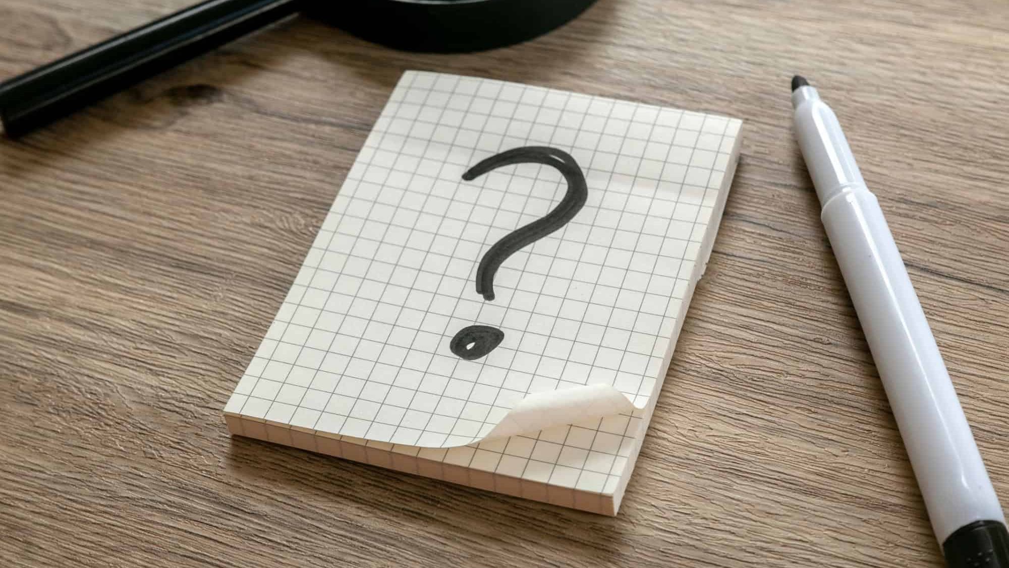 Question Mark on Graph Paper Notepad on Wooden Surface