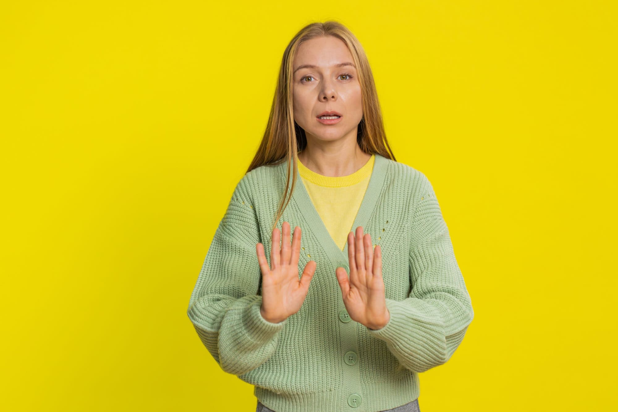 Hey you, be careful. Strict middle-aged mature woman warning with admonishing hands gesture saying no be careful, scolding and giving advice to avoid danger disapproval sign. Girl on yellow background