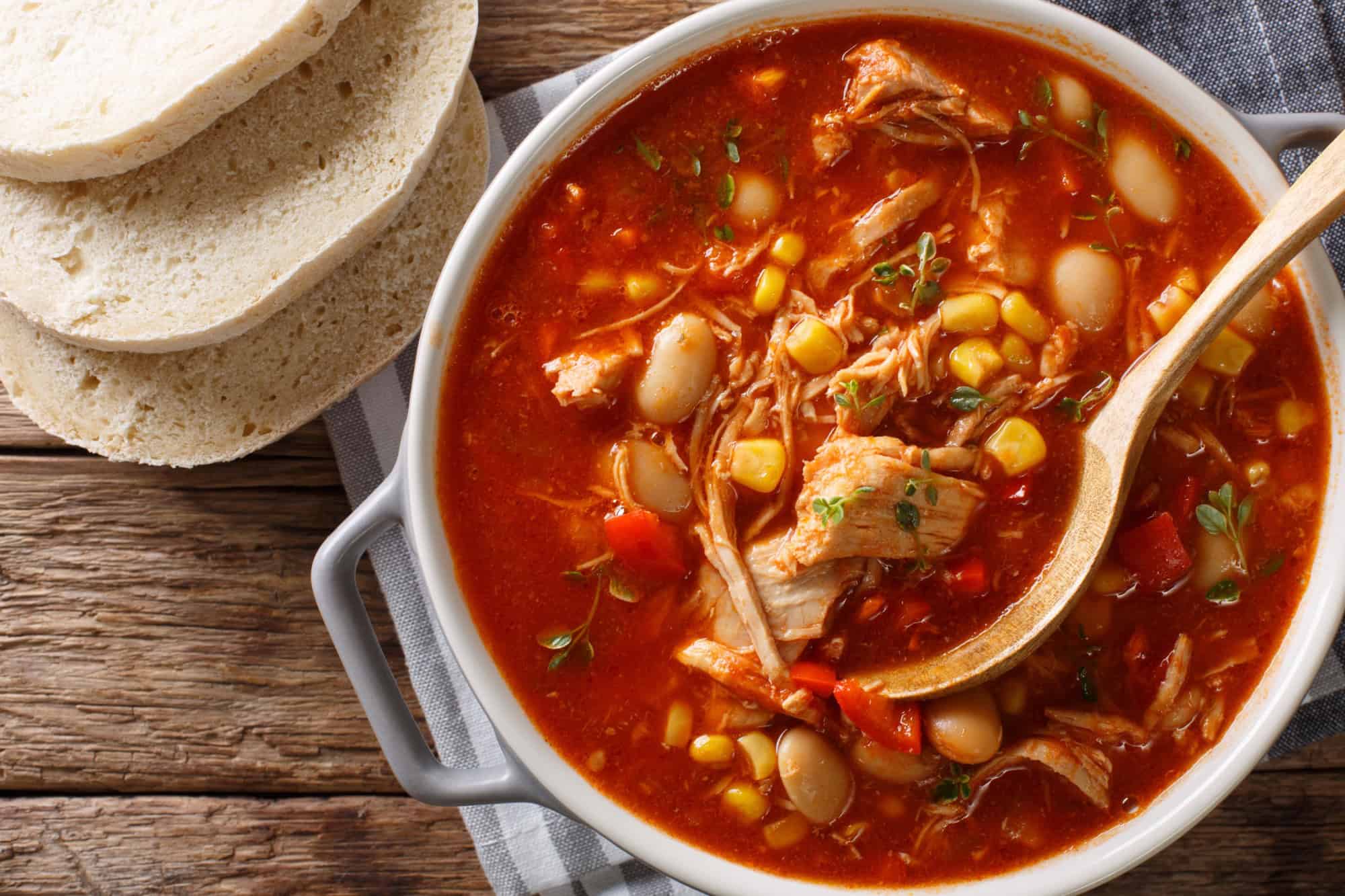 Brunswick Stew - thick, flavorful and hearty one-pot stew with vegetables and meat on a chicken broth and BBQ sauce close-up in a bowl on the table. Horizontal top view from above