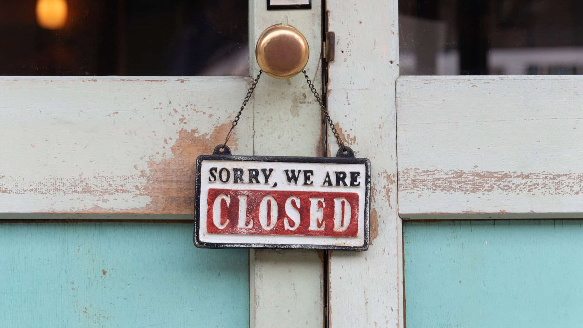 sorry we are closed sign hanging outside a restaurant, store, office or other