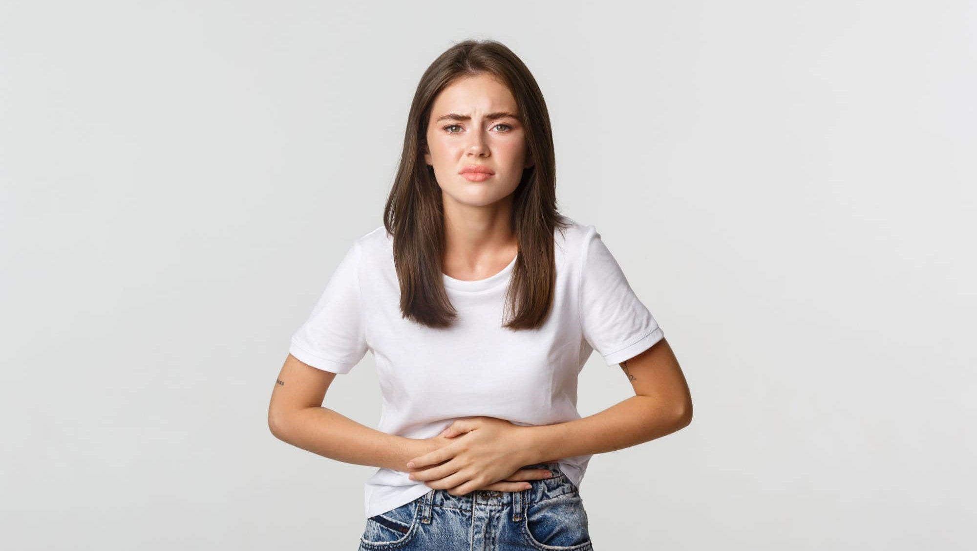 Woman having stomach ache, bending and holding hands on belly, discomfort from menstrual cramps. Girl feeling nauseous