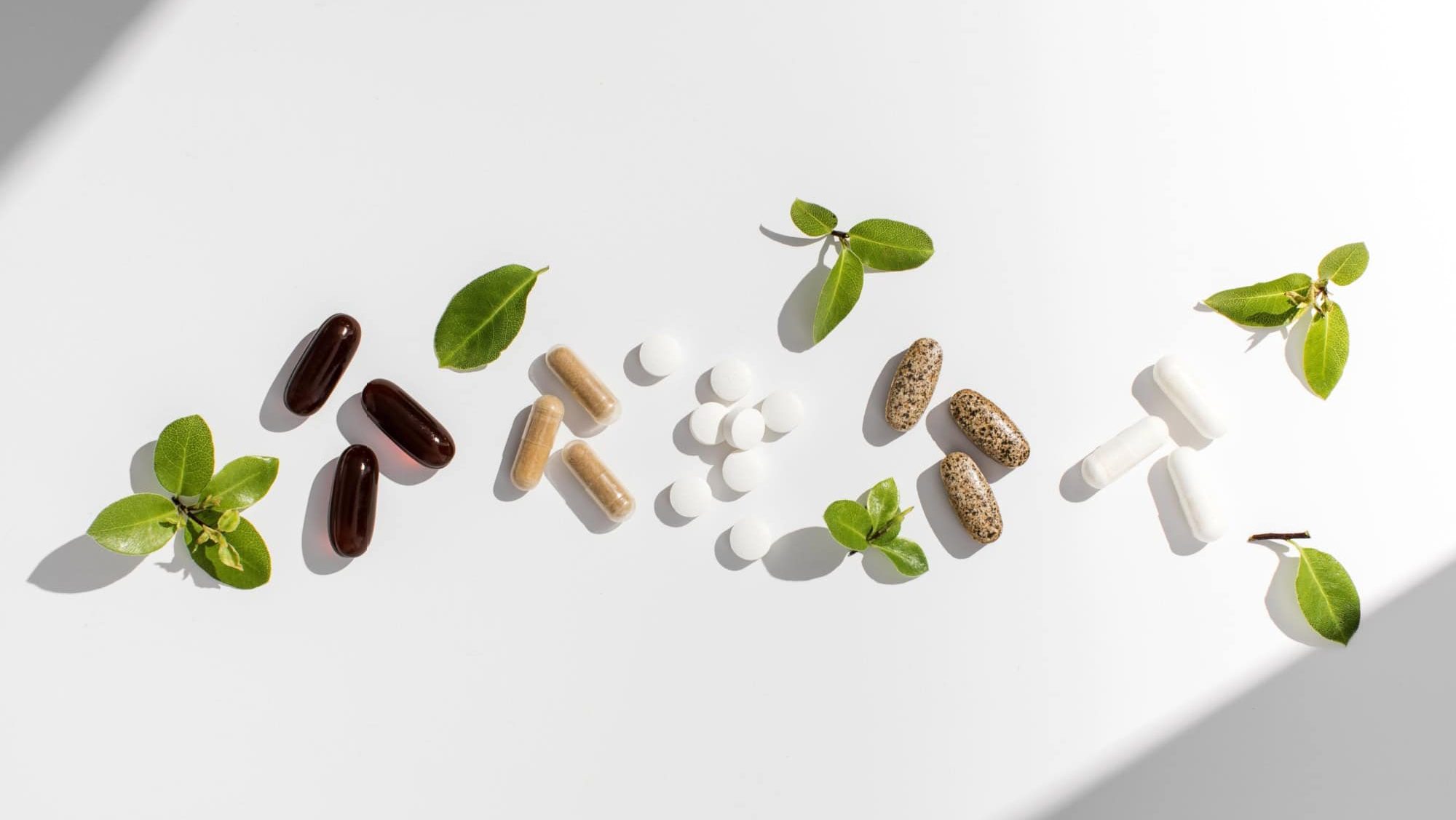 Various vitamins, tablets and dietary supplements with natural formulations on a white background.