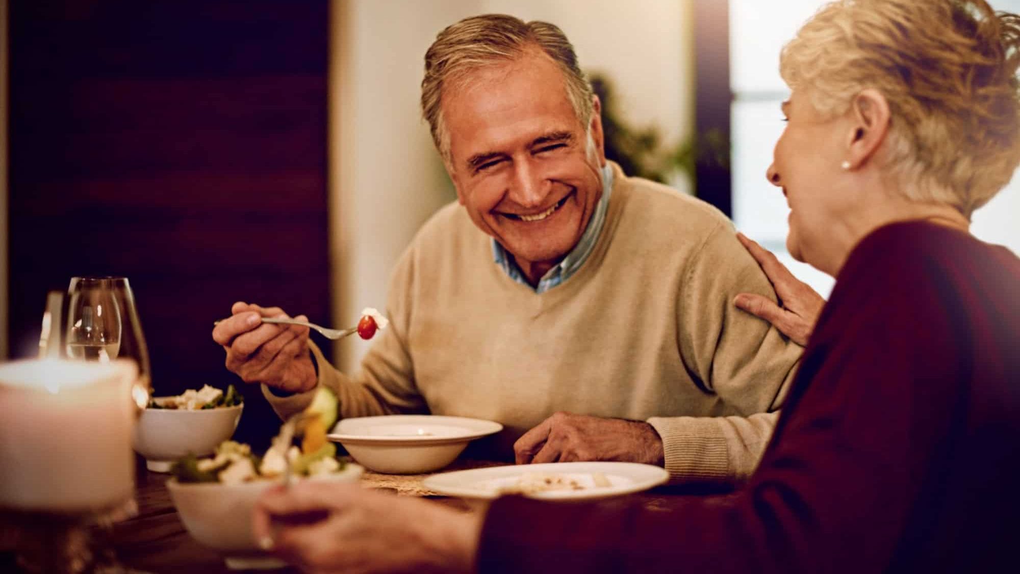 Senior, couple and dinner on date with love on anniversary in retirement with happy marriage. Elderly people, laughing and eating together in fine dining restaurant with food, care and relationship