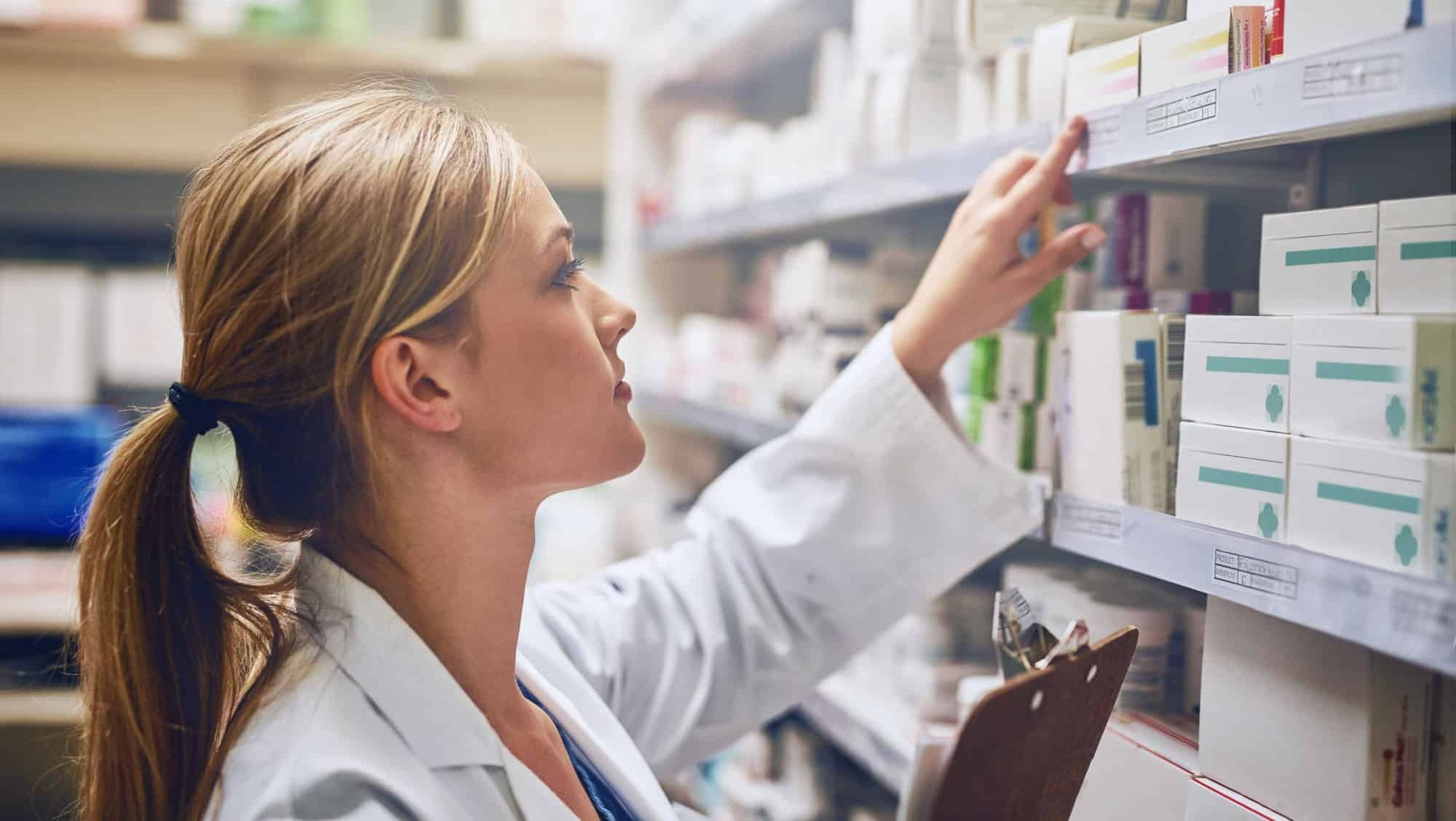 Woman, pharmacist or reading medication for stock check or inventory at pharmacy for pills information. Clipboard, medical internship or girl by shelf for pharmaceutical drugs for boxes or product