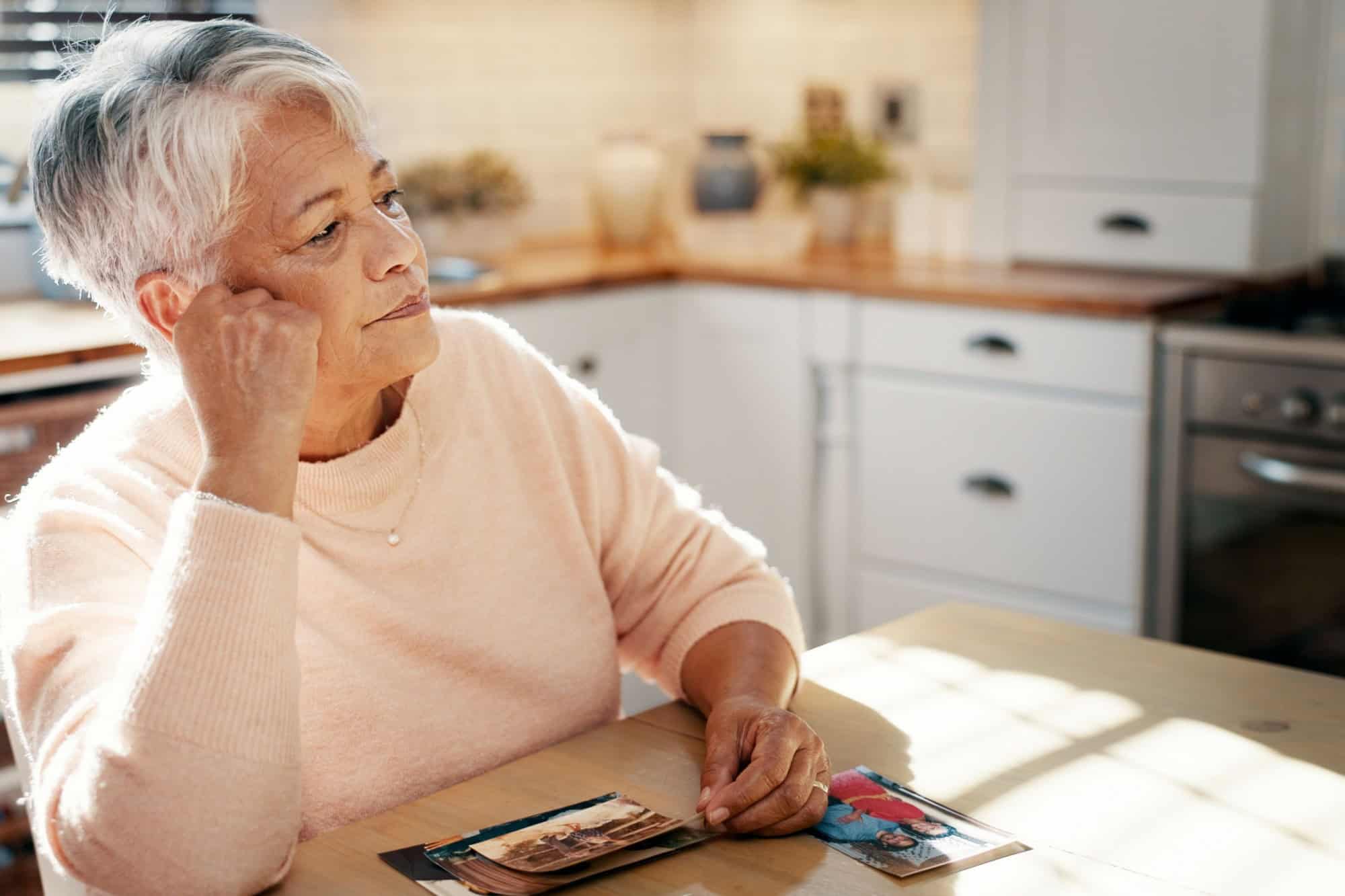 Thinking, senior woman and picture at house for mourning loss, memory past and reminder for history. Elderly person, grief and old image with loneliness, remember partner and nostalgia for retirement