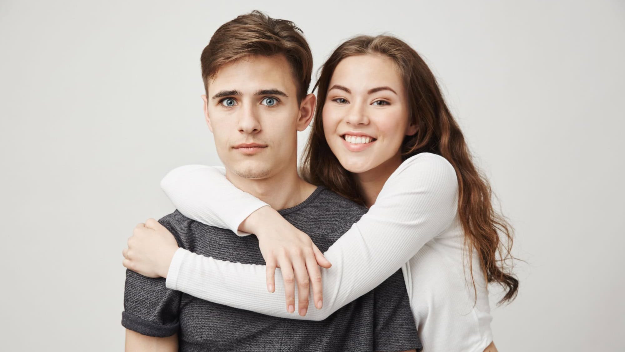 Picture of two best friends hugging in front of the camera. Friendship and romance concept. Girl and boy were friends since school but guy always felt something more so it is awkward when she hugs him