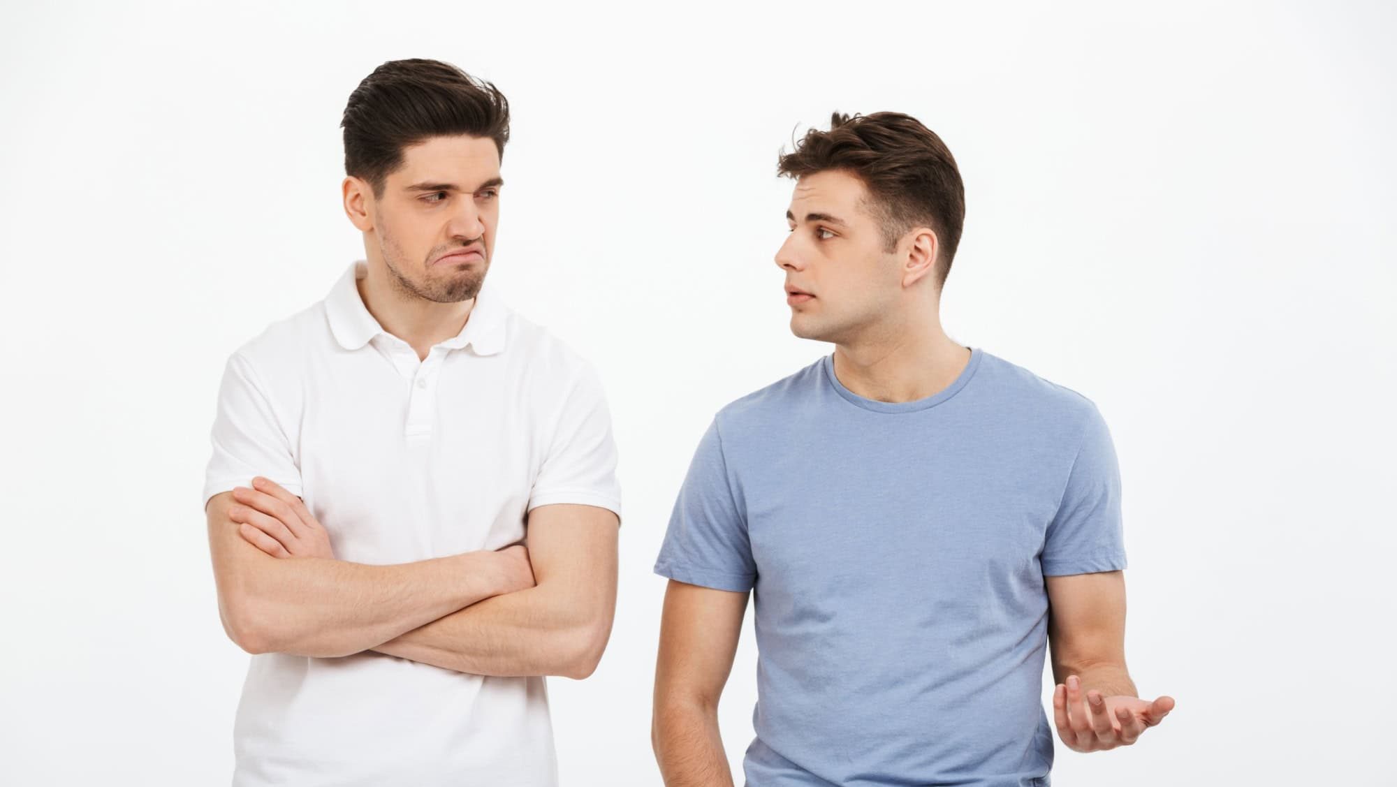 Portrait of two upset young men arguing isolated over white background