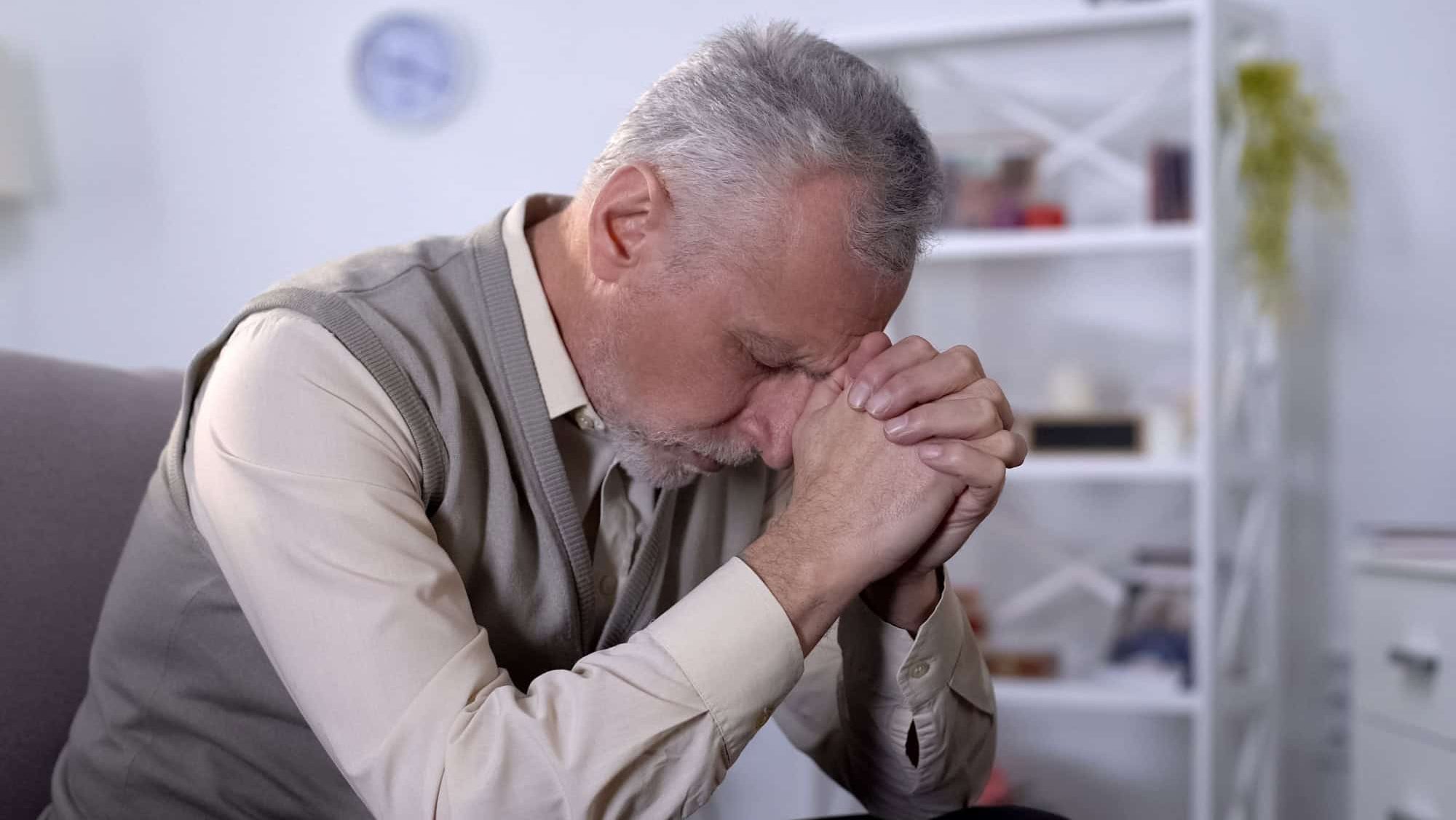 Elderly man sadly bowed head, feeling lonely and depressed, old age crisis