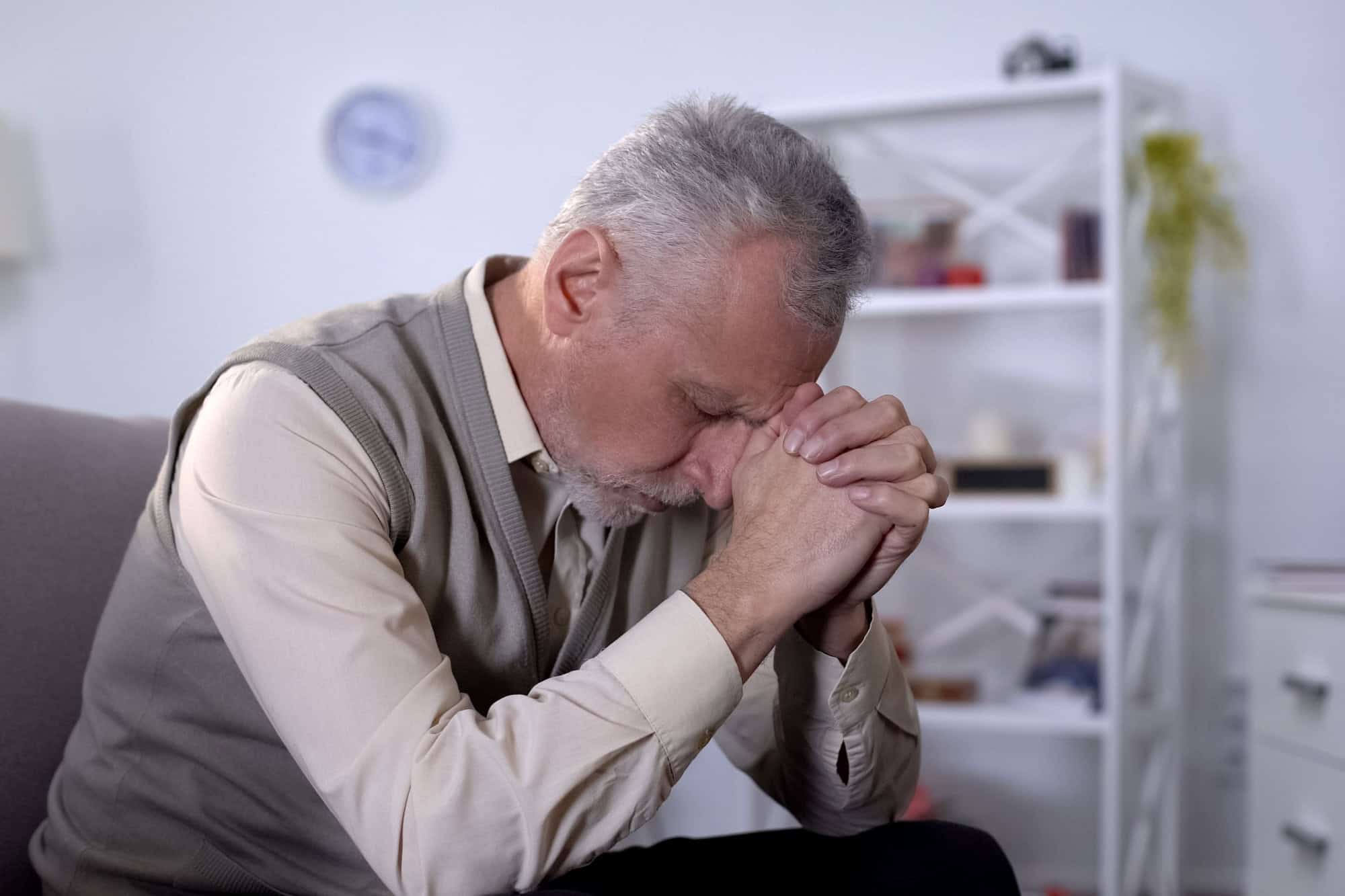 Elderly man sadly bowed head, feeling lonely and depressed, old age crisis