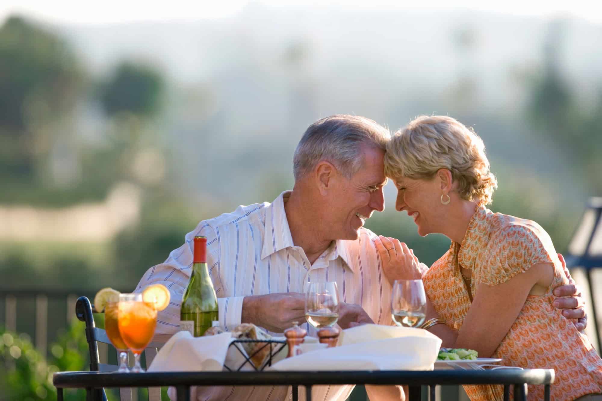 Loving mature couple eating at outdoor restaurant table