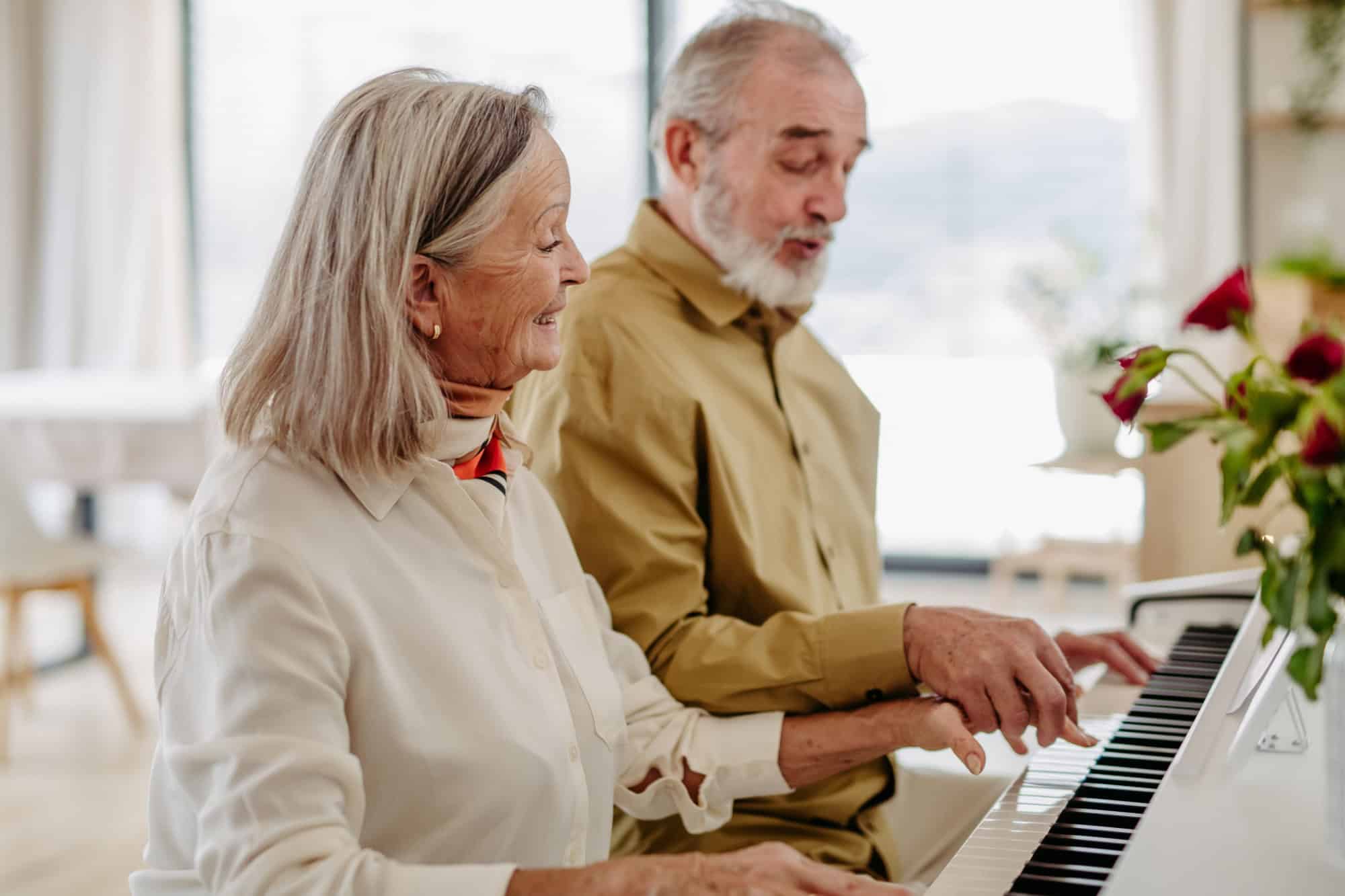 Senior couple playing on piano together at home.