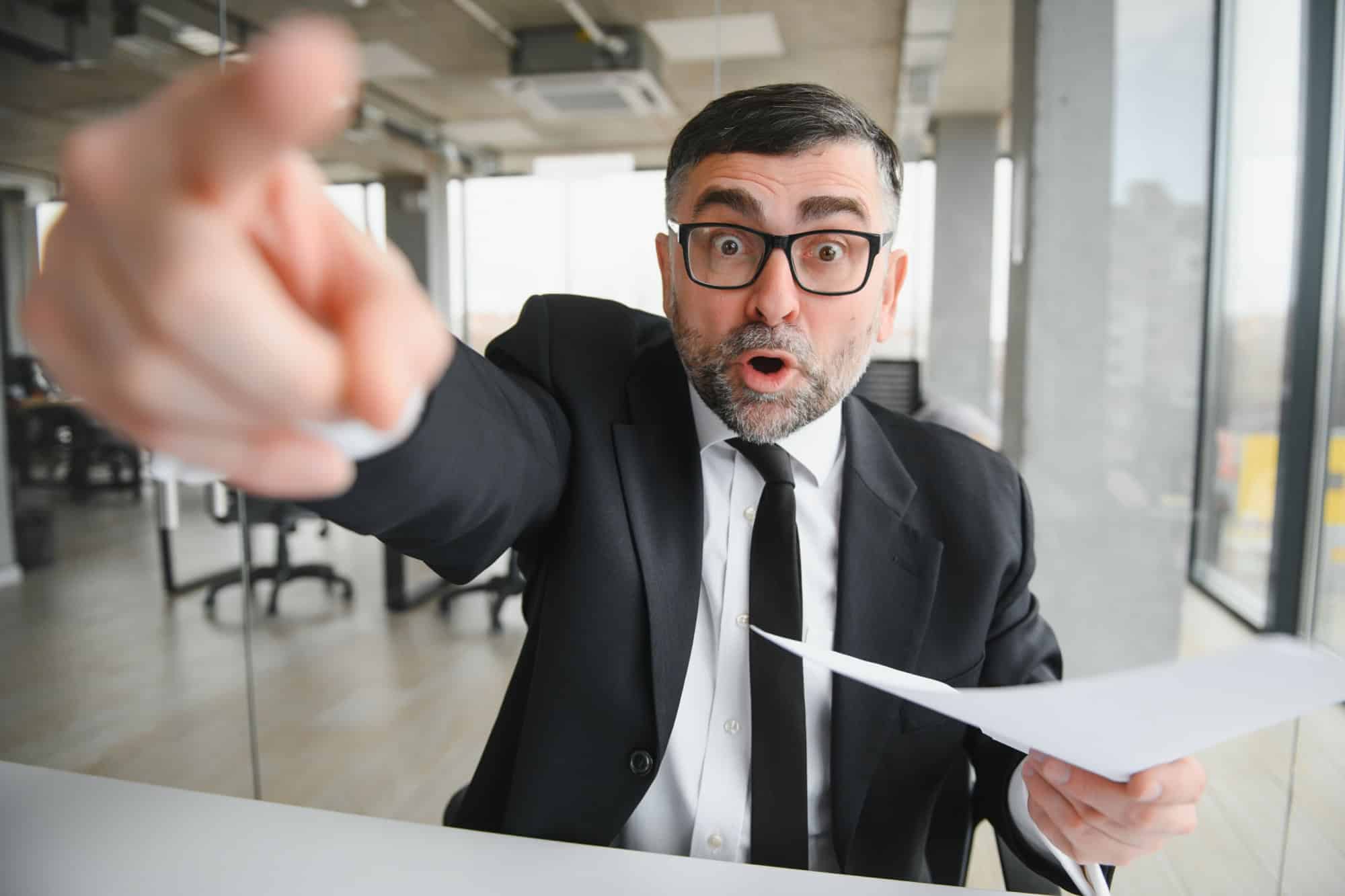 Angry businessman sitting at the table and screaming over