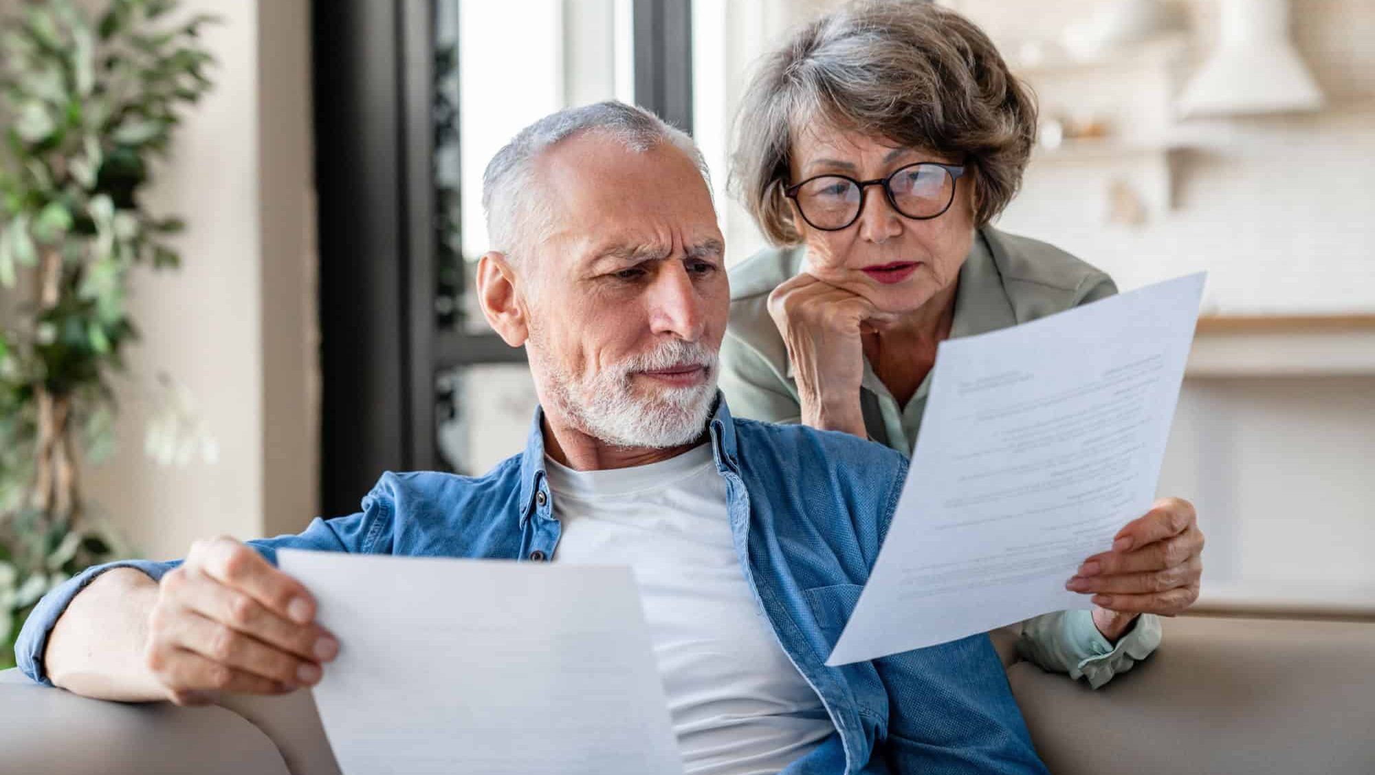 Senior old elderly spouses grandparents reading documents, having issue problem debt with money loss, doing paperwork together at home. Mortgage, loan and commerce procedures