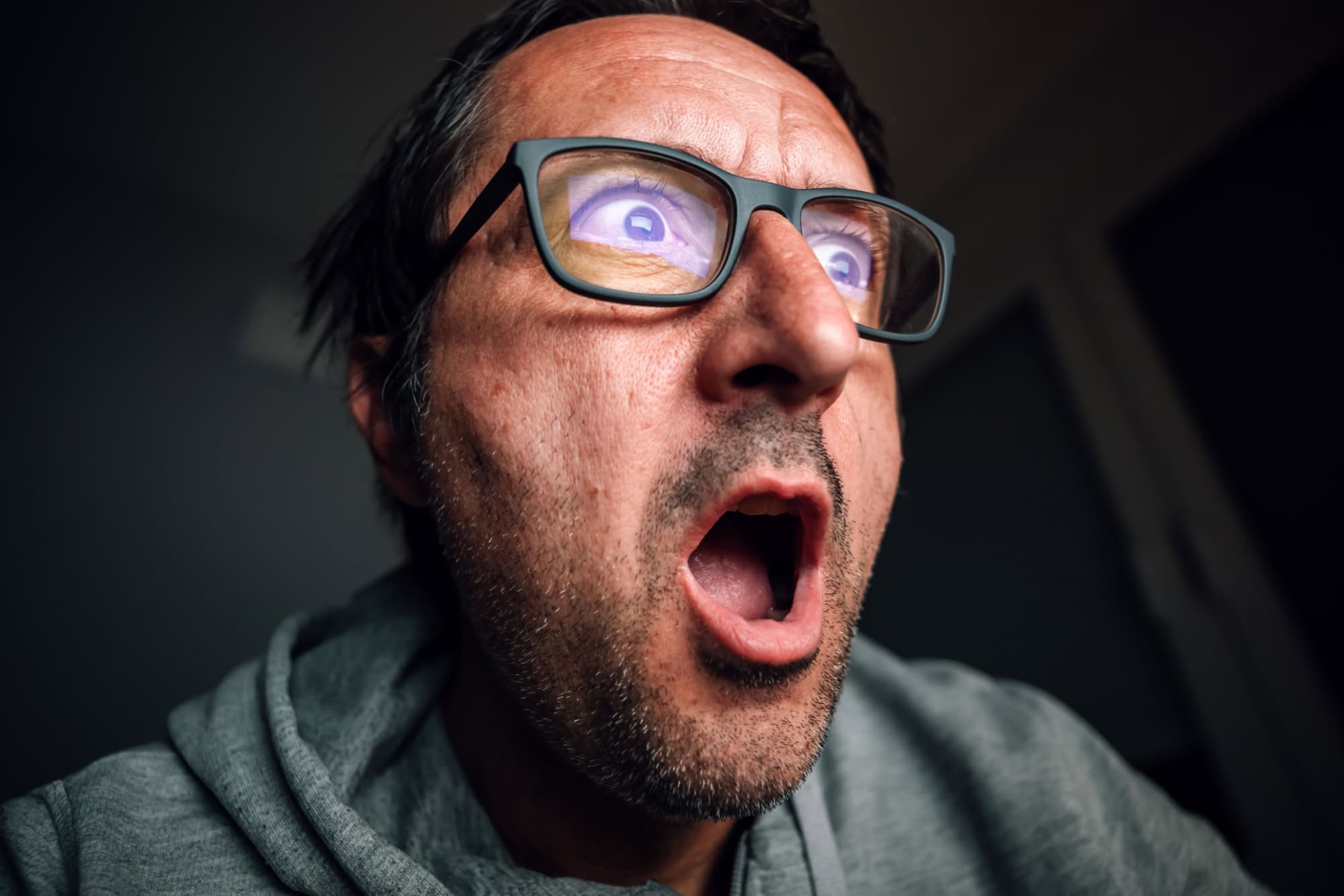 Surprised and shocked man looking at computer screen while browsing internet or social media, selective focus