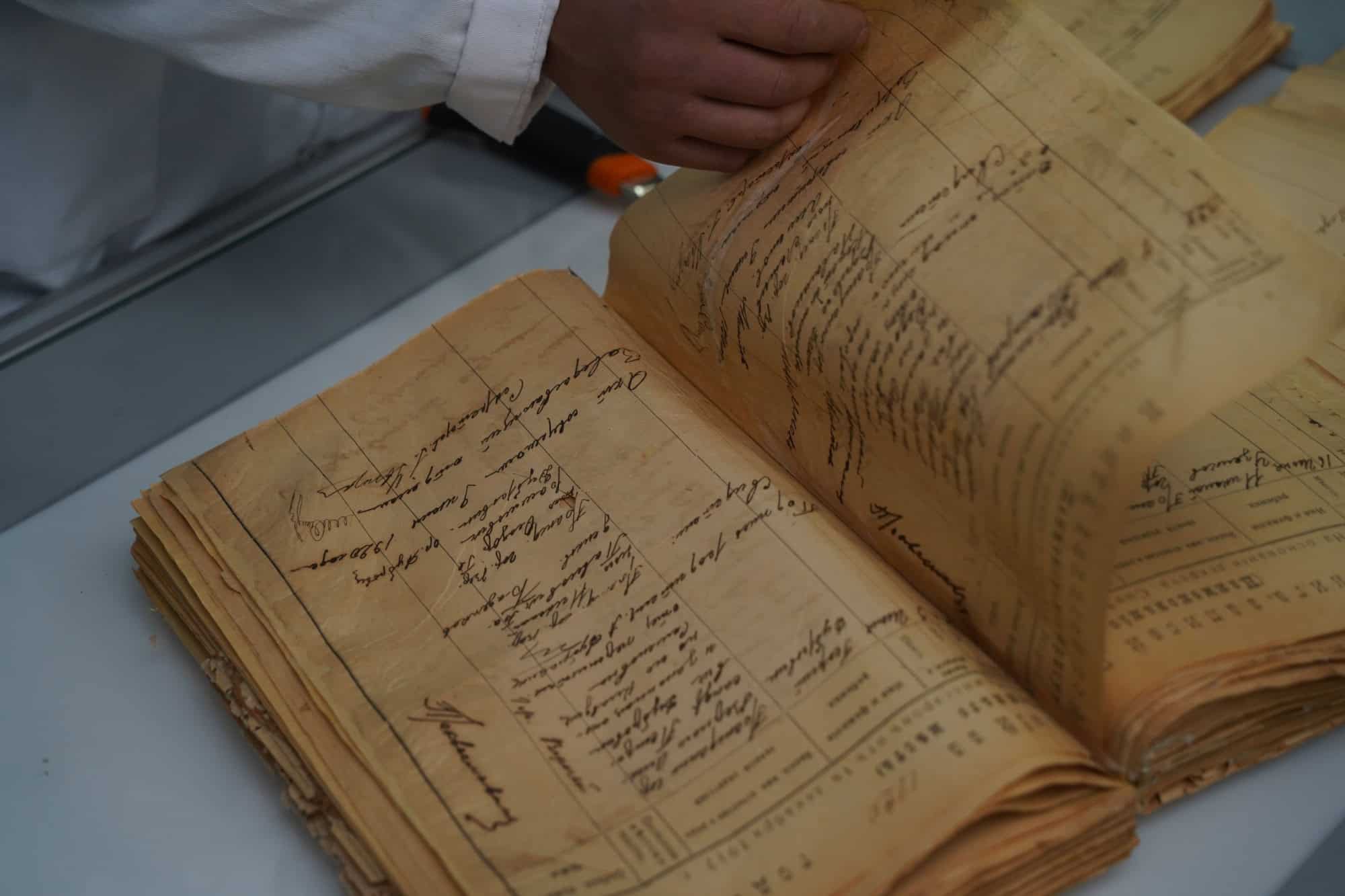 An employee of the city archive is restoring an old birth registration book for residents.