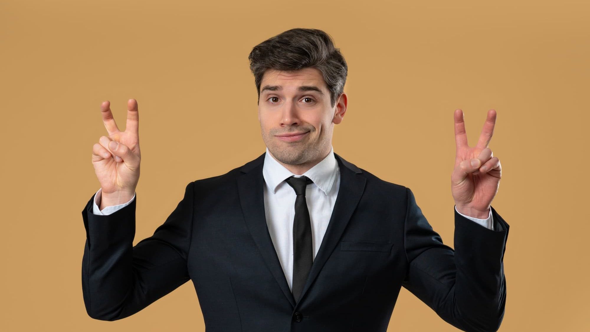 Smirking suspicious 30s businessman in formal wear with hands two fingers air quotes gesture on warm yellow, sarcasm. Not funny. High quality
