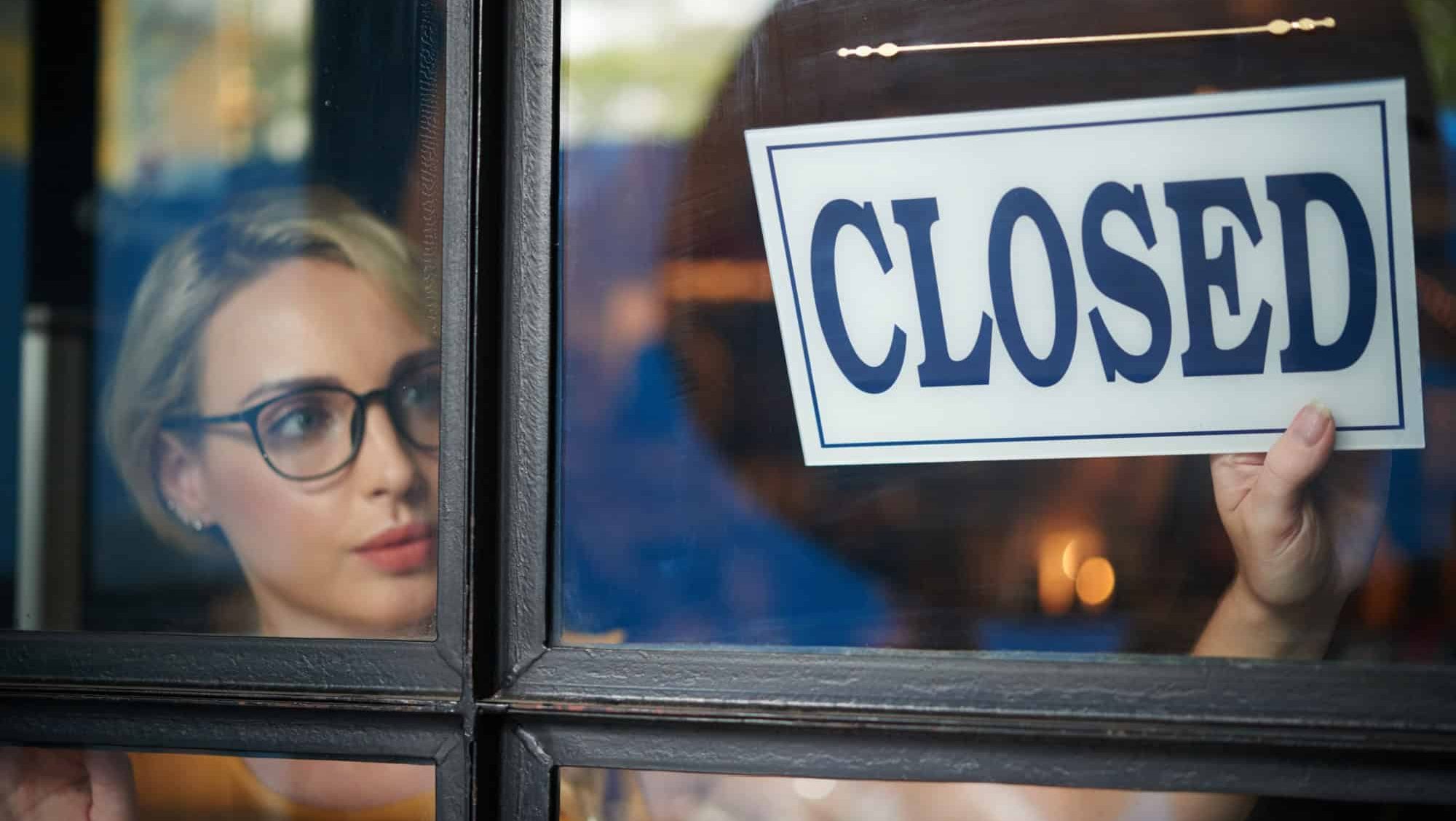 Pretty young shop owner turning closed sign