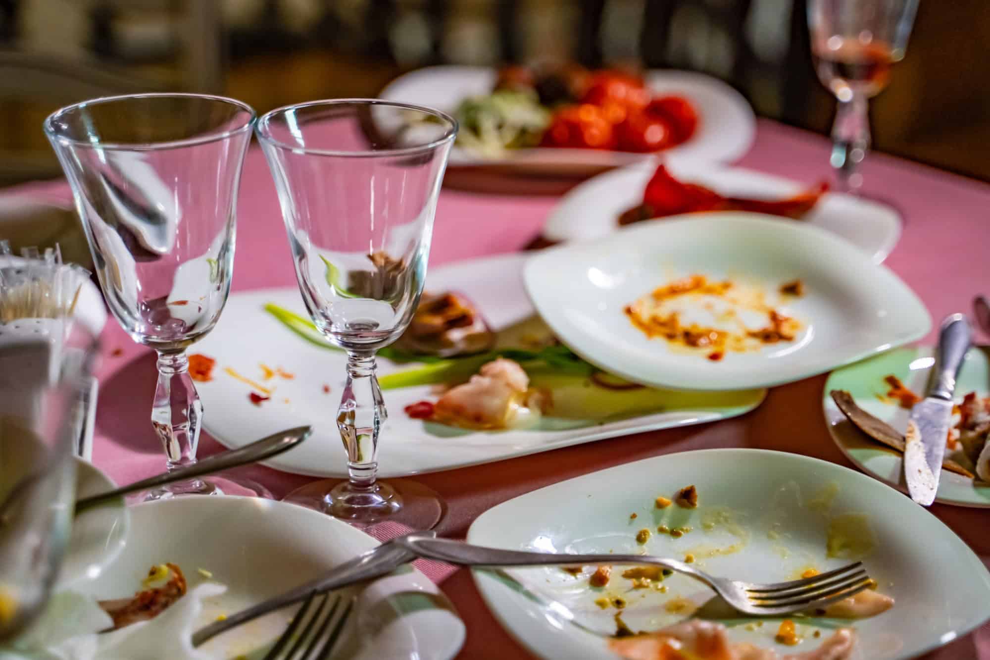 Dirty plates on the table after dinner party. Leftovers, empty plates after banquet.
