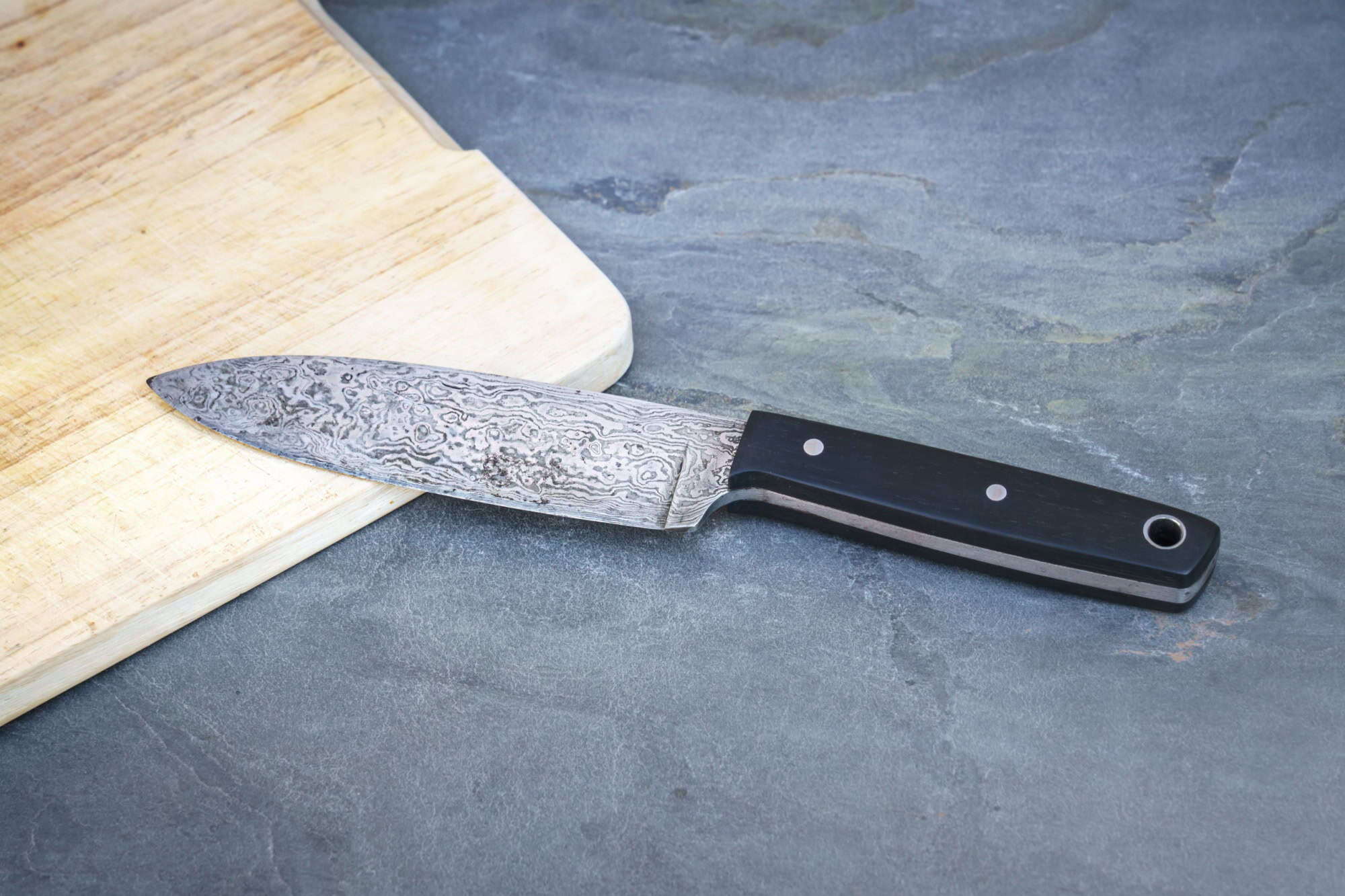 An image of a Damascus steel knife on a wooden board