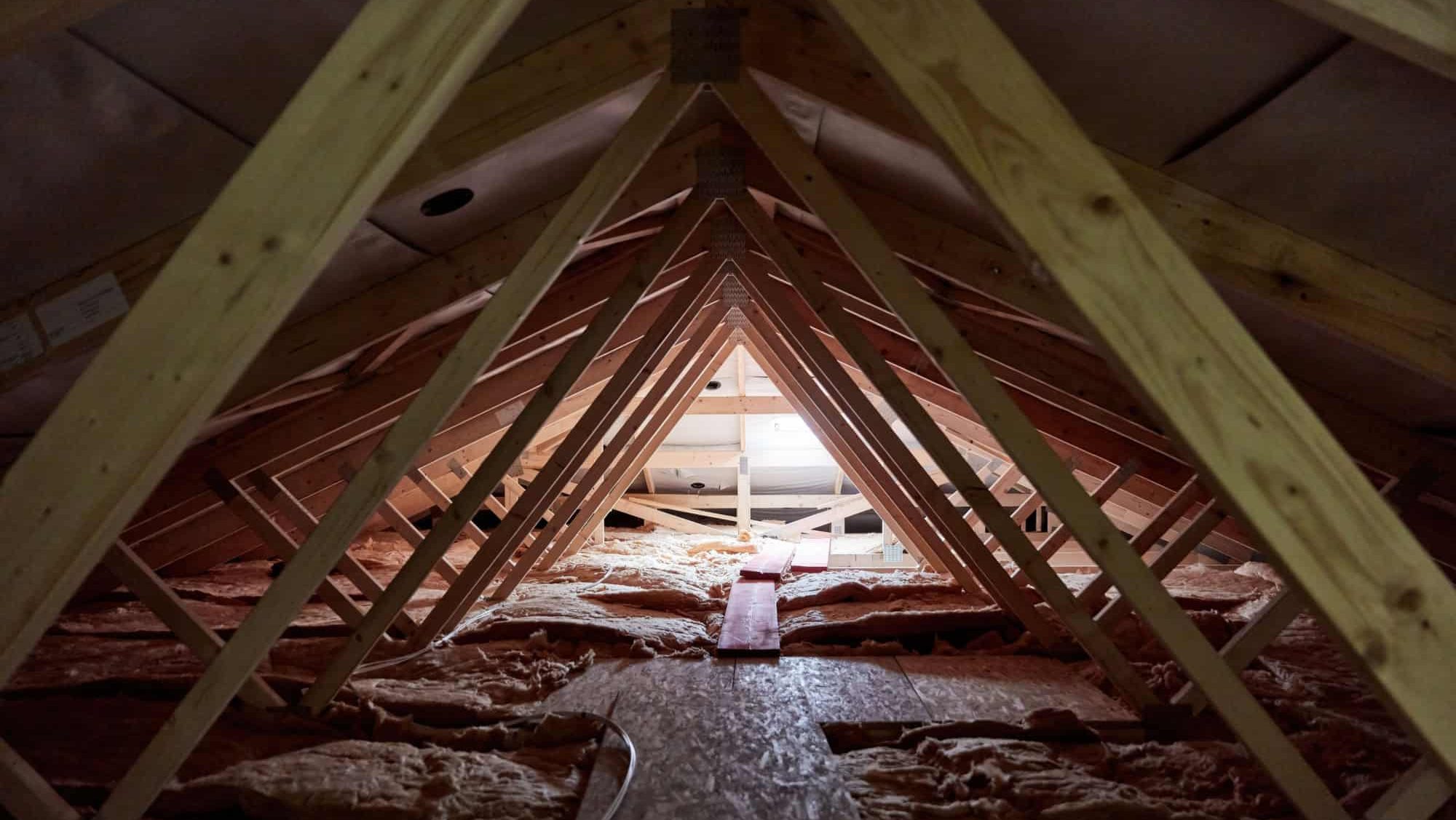 Dark attic with a small window and wooden beams in a new build house