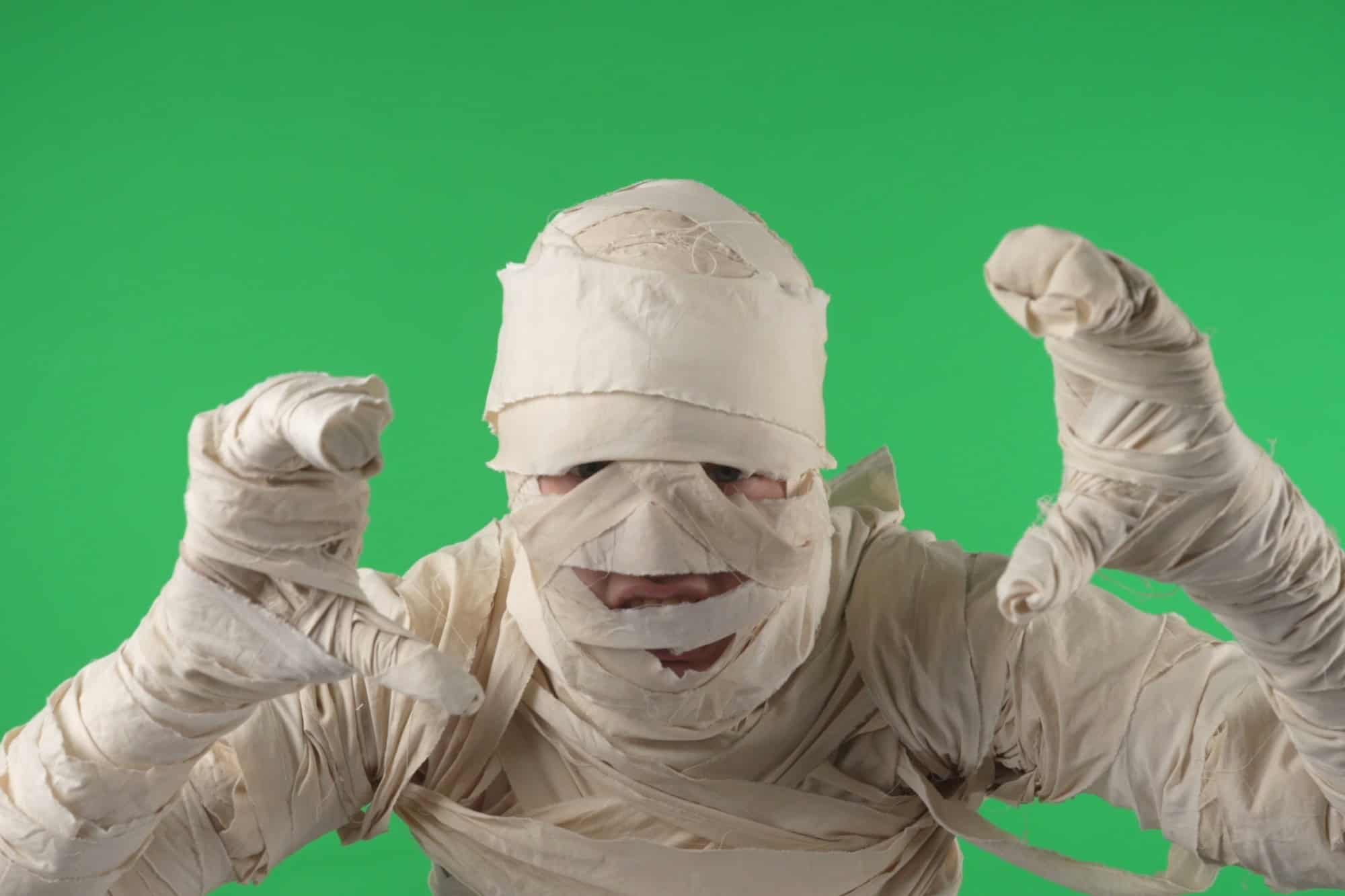 Green screen isolated chroma key photo capturing a mummy jumping at the camera to scare, booing and roaring, pulling hands towards the camera.