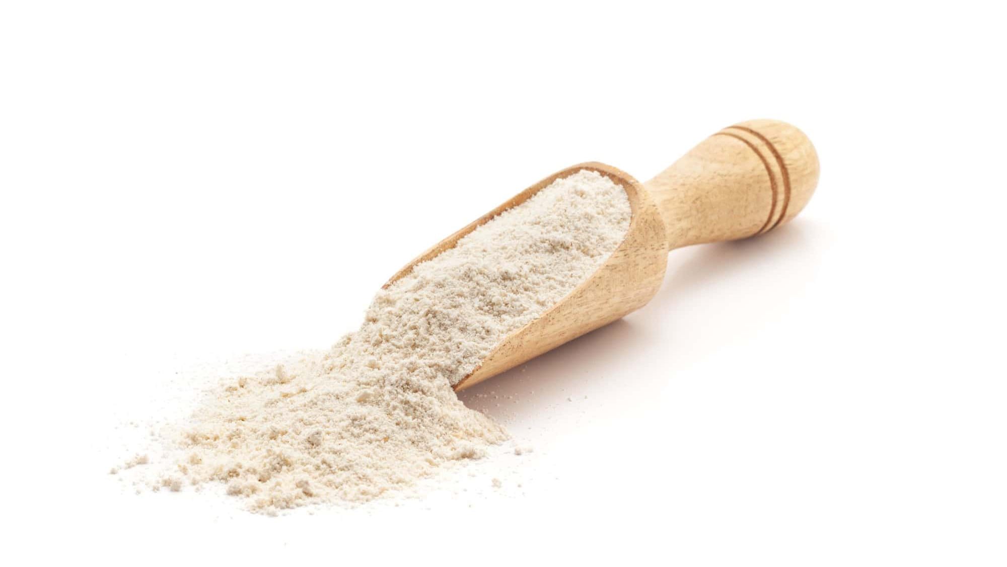Front view of a wooden scoop filled with flour