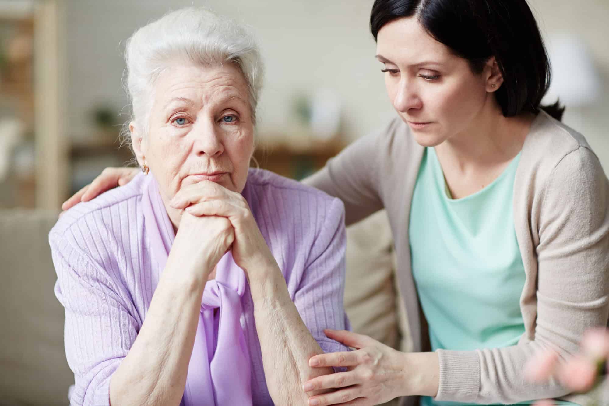 Young woman comforting her discontent or offended aged mother