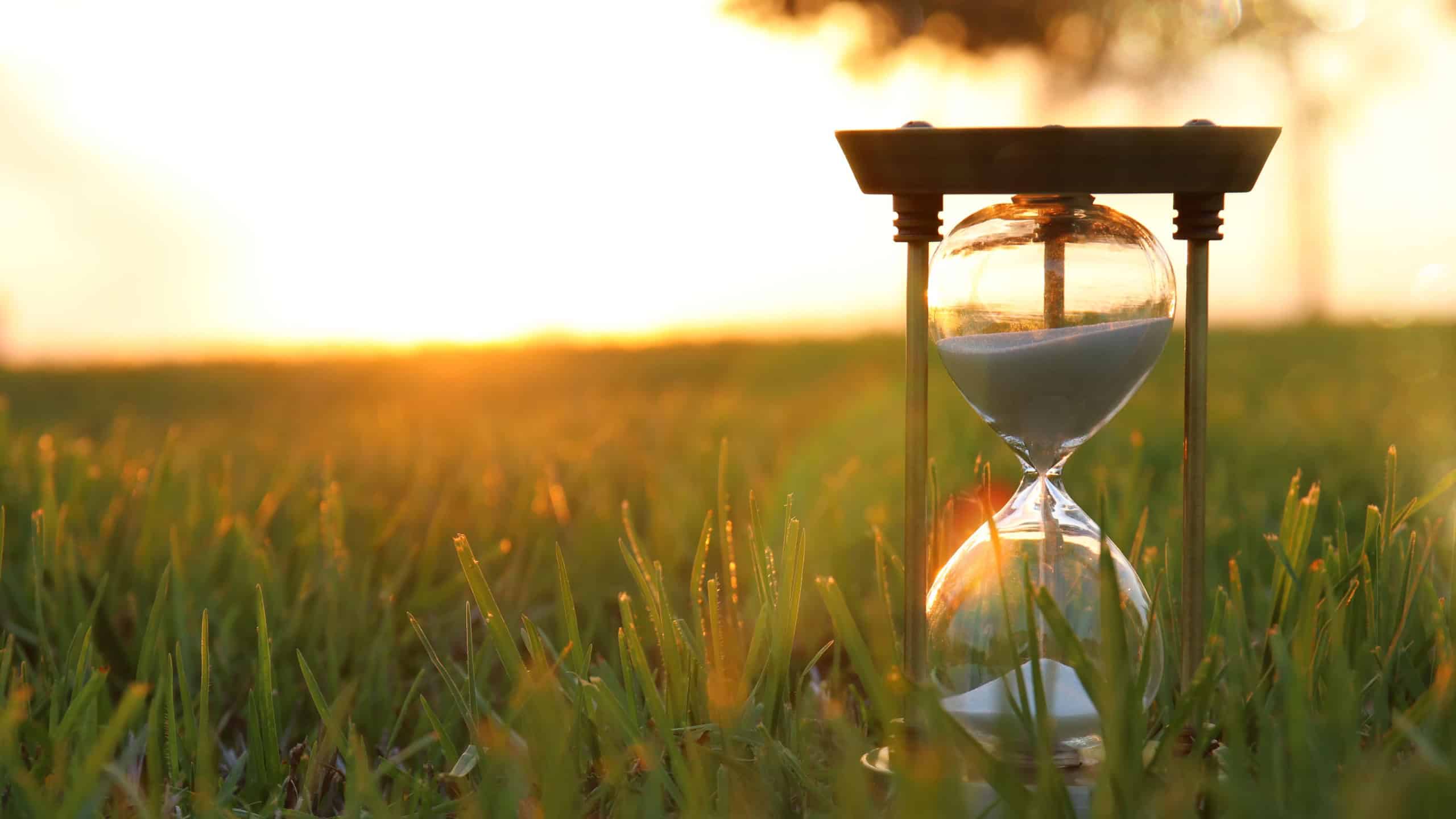 Hourglass in the grass time during sunset. vintage style