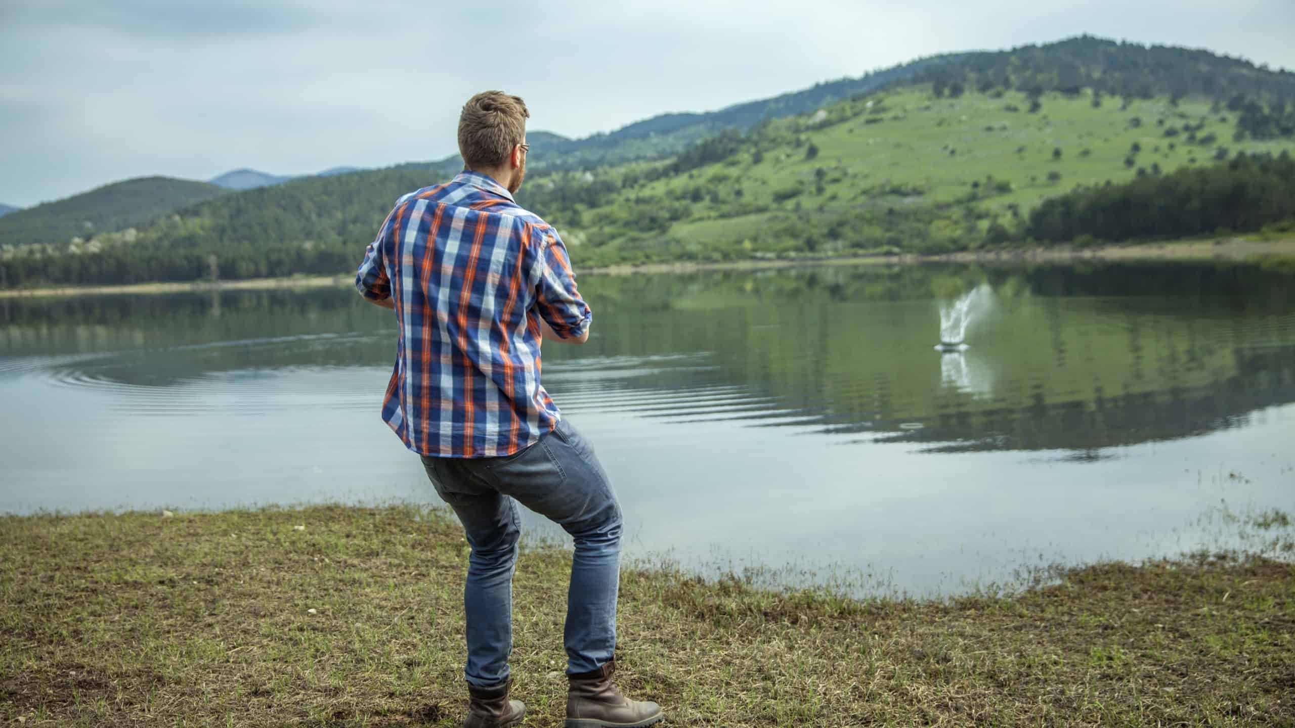 A young man skipping a stone on lake water