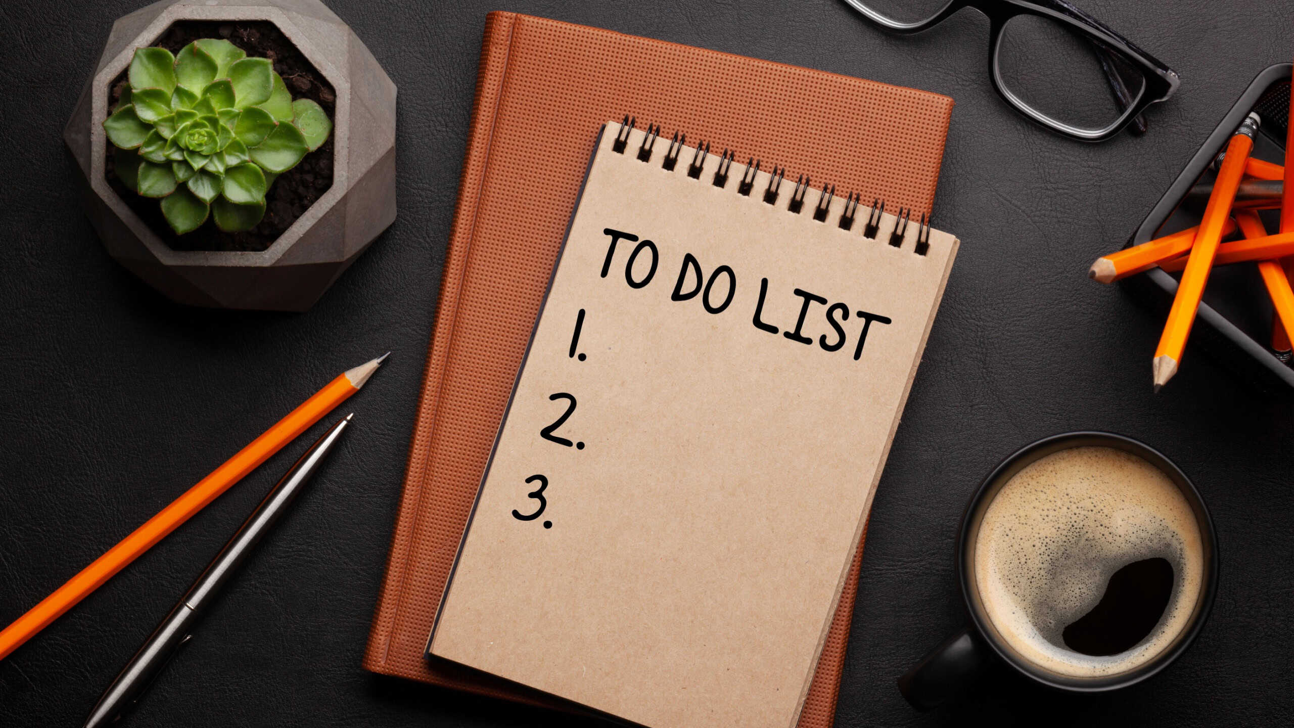 Office desk with supplies and coffee cup over black leather table. Top view flat lay with notepad with to do list