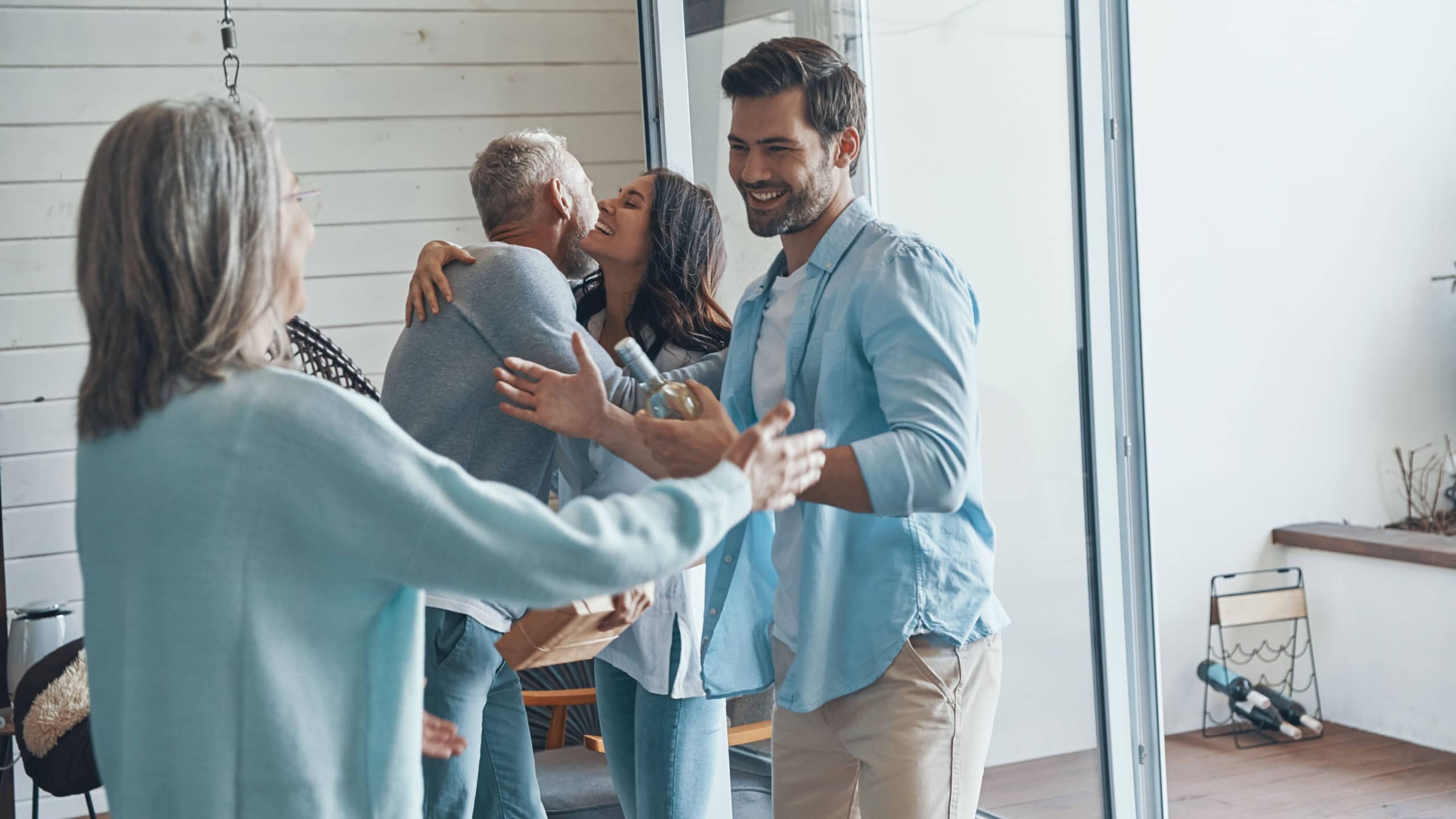Smiling senior parents meeting young couple inside the house