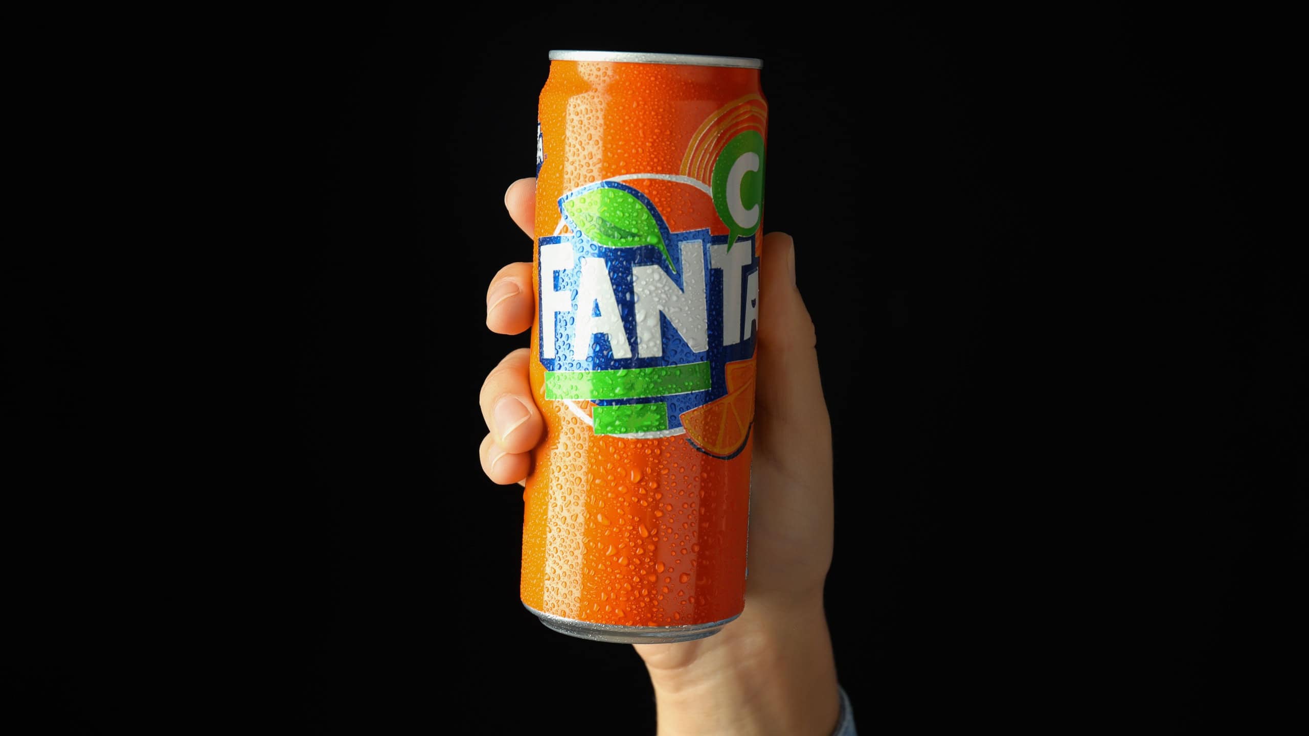 Odessa, Ukraine - September 23, 2021: Female hand holds Fanta can on black background.