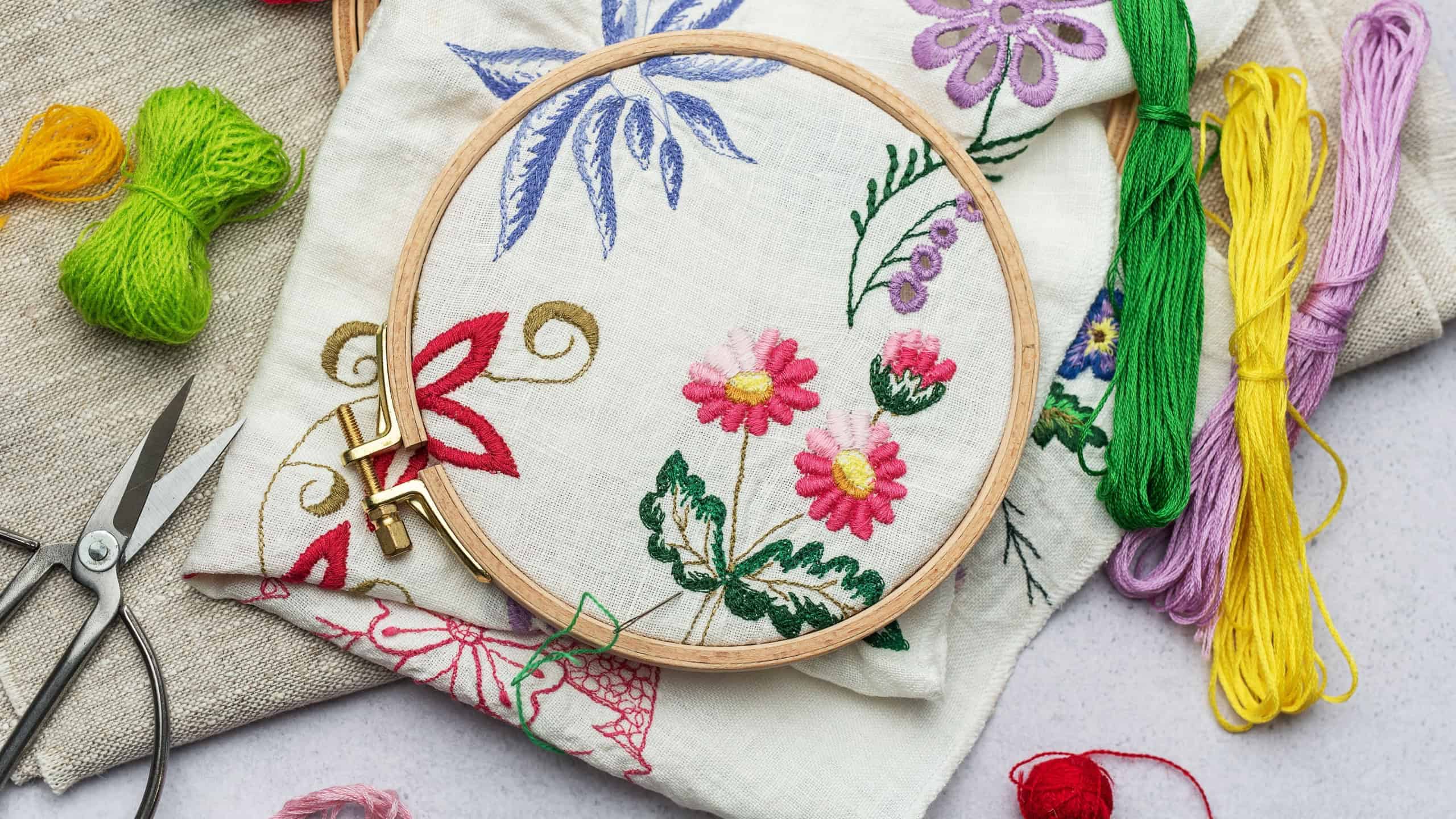 The process of hand embroidering a napkin with colored threads on white fabric.