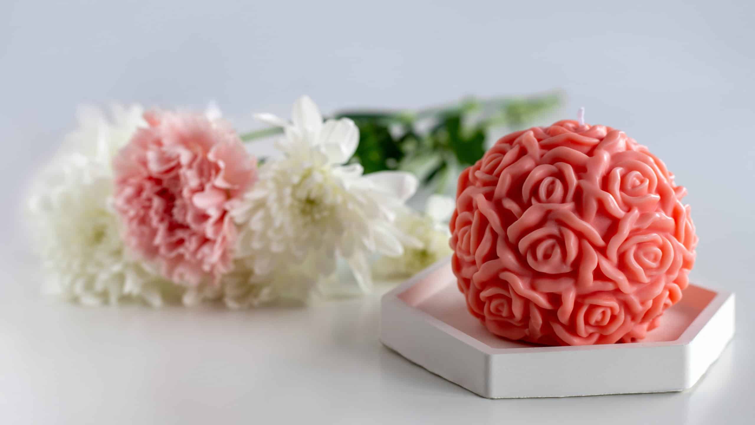 Red soy wax candle on a table with flowers. Home decor. Cozy interior.