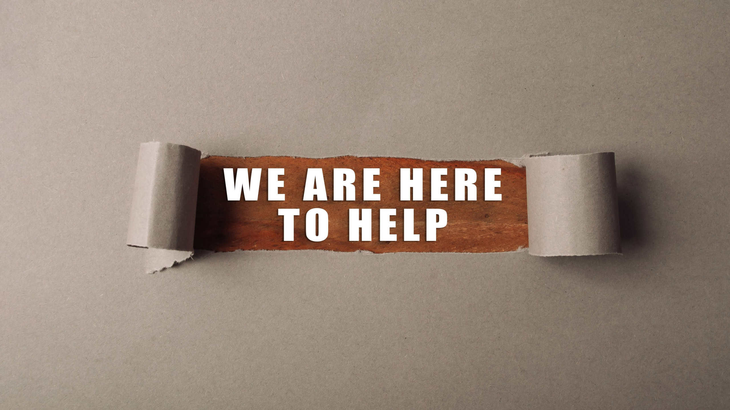Torn piece of paper with the words We are here to help written on it. The image has a sense of urgency and a call to action