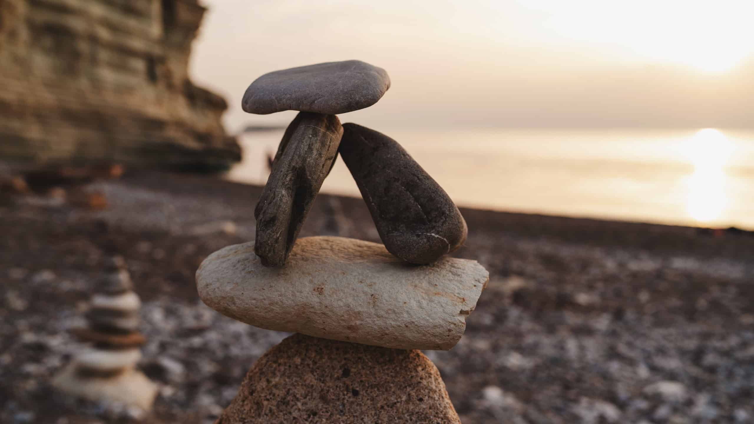 Balanced Stone Cairns on a Rocky Beach at Sunset.
