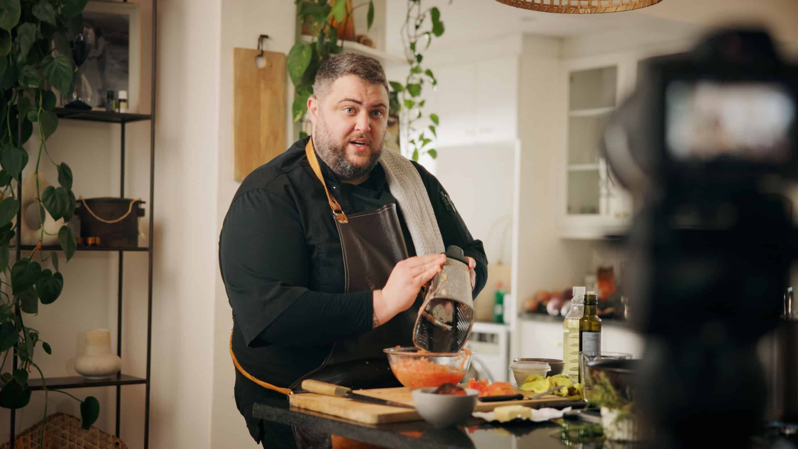 Ingredients, cooking and man with live streaming in kitchen for dinner recipe, meal prep or video recording. Culinary influencer, content creation or person with cuisine tutorial or nutrition in home