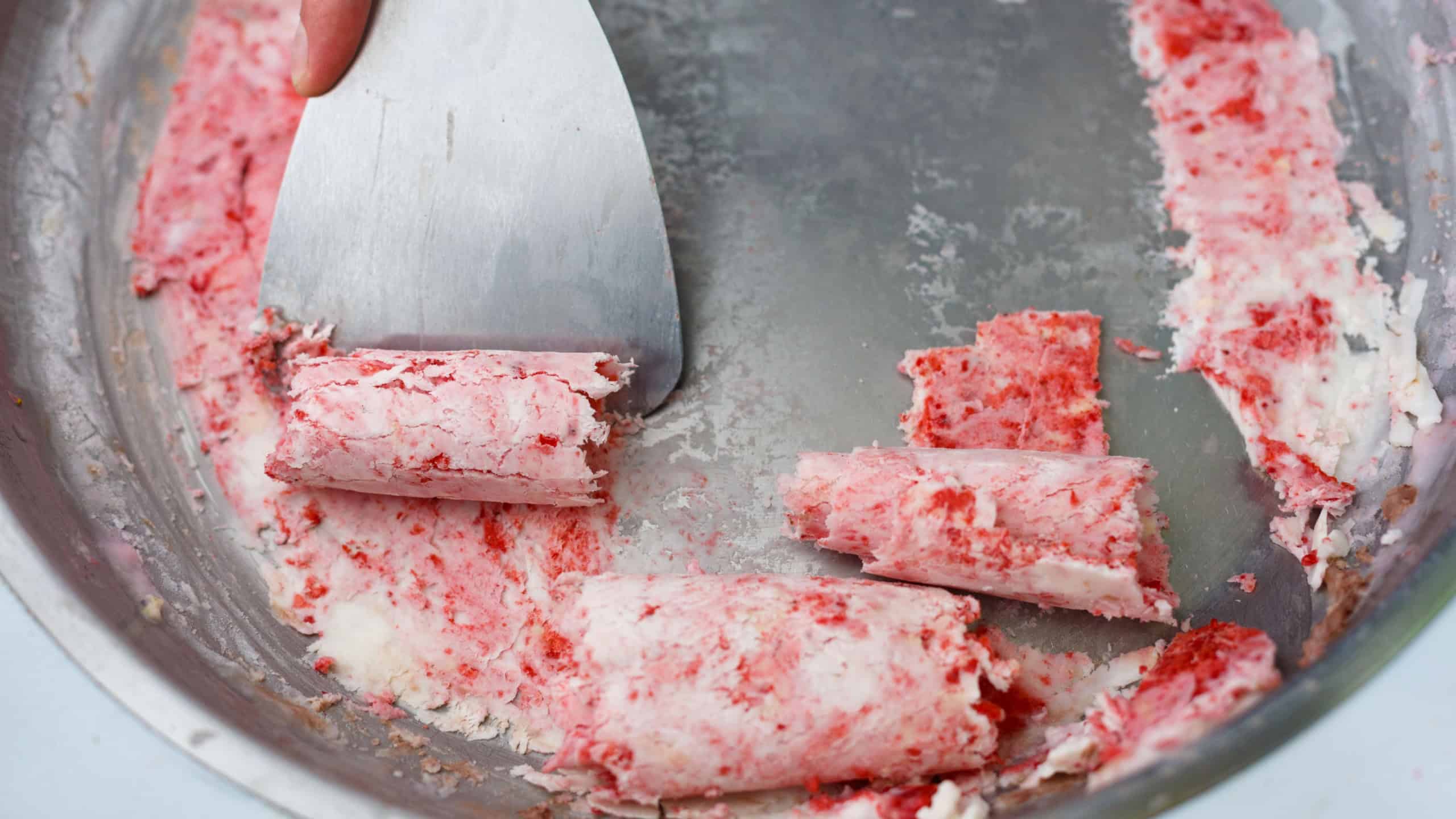 Thailand stir-fried ice cream rolls at freeze pan. Rolled ice cream, hand made ice cream dessert. Stir-fried ice-cream from milk and berry jam. Fried ice cream machine with steel chilled pan.