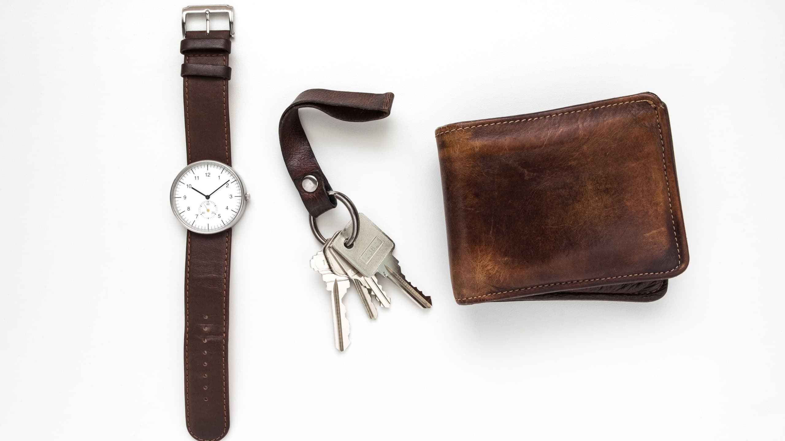 Top view of everyday carry objects made by brown leather on white background