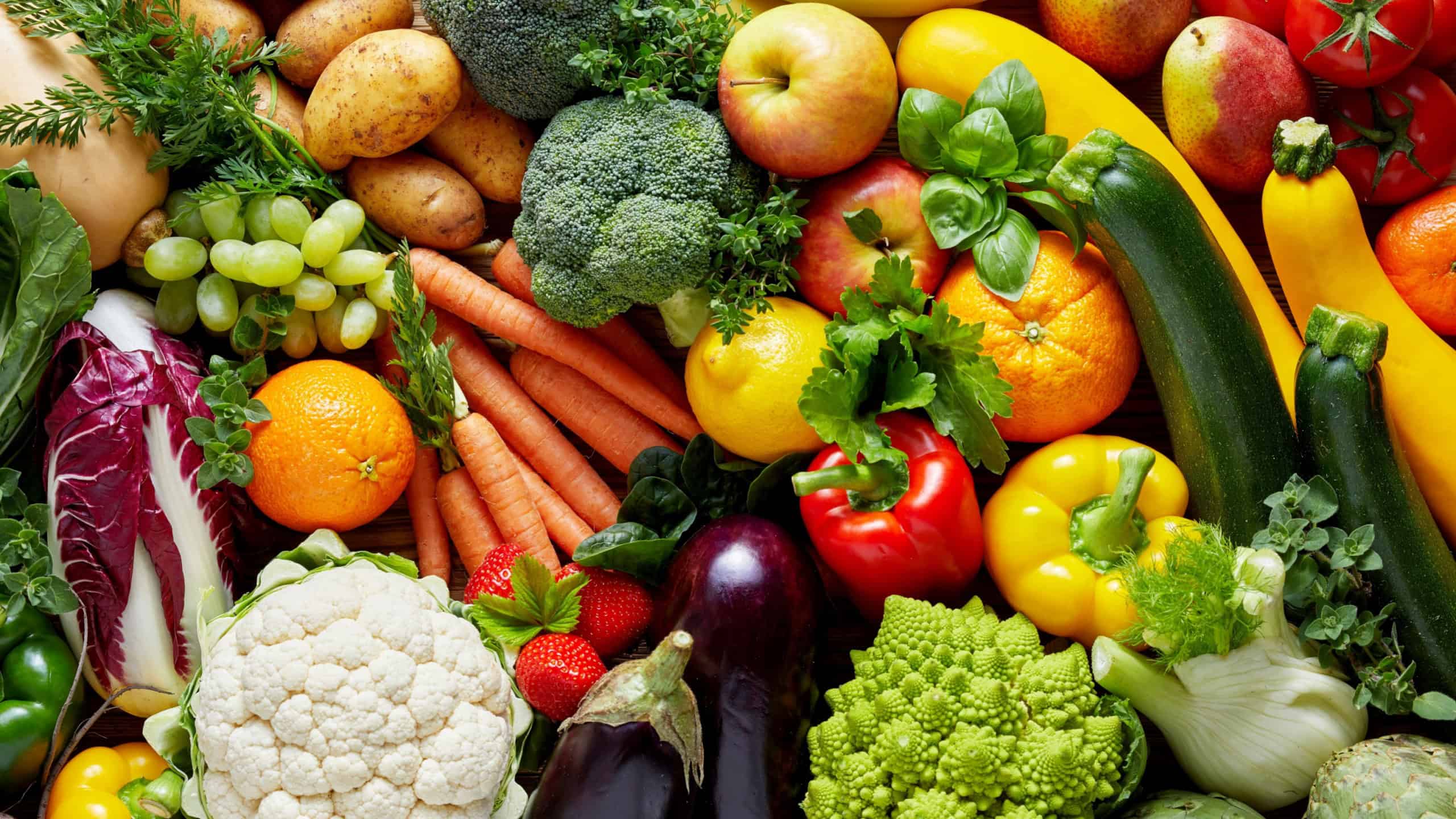 Different colorful fruits and vegetables all over the table in full frame studio shot