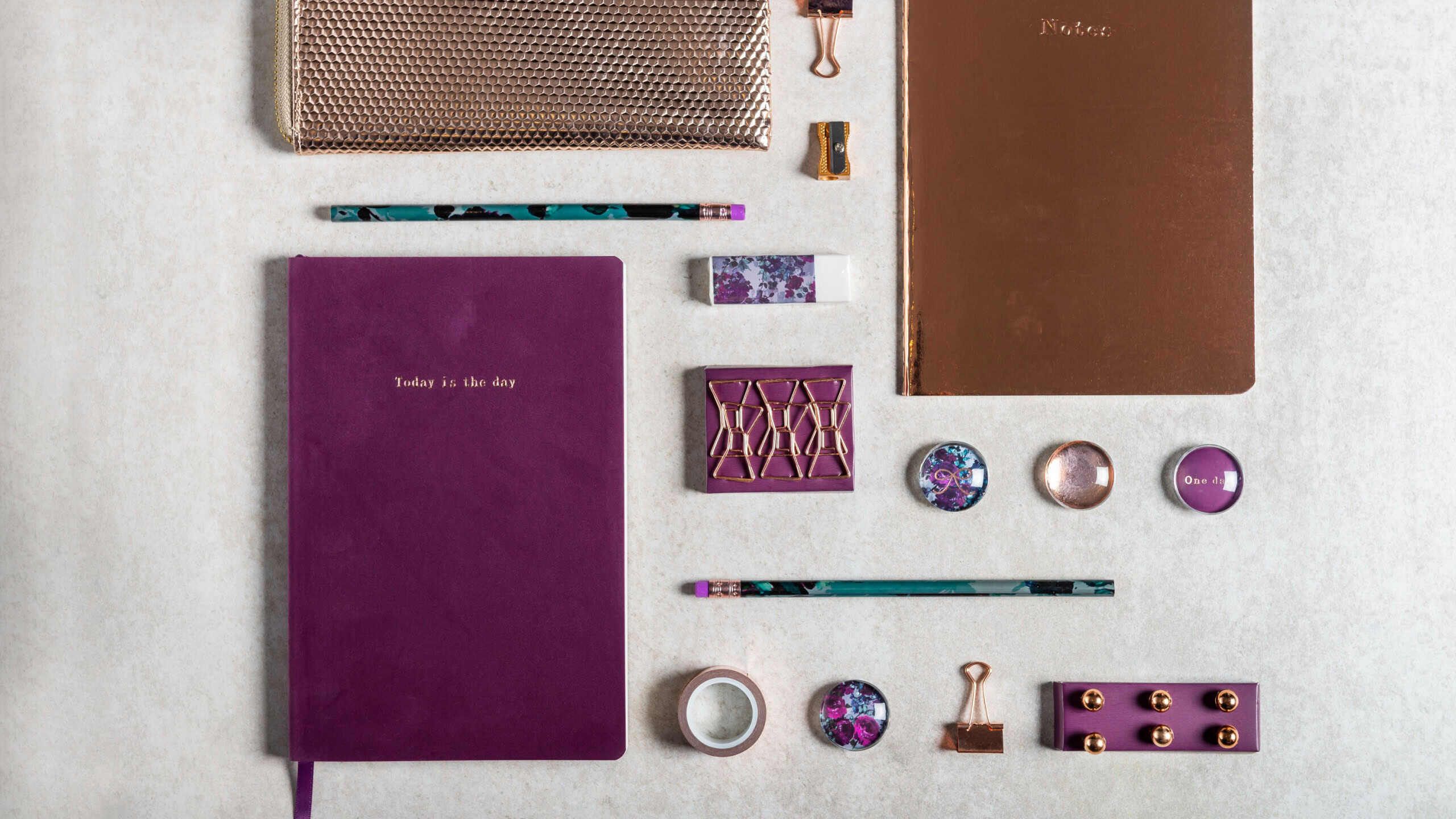 Notebooks for writing Dreams and Ideas, with different gold and maroon Stationery laying on grey background. Top View. Idea of Girly Office settings. Flat lay style