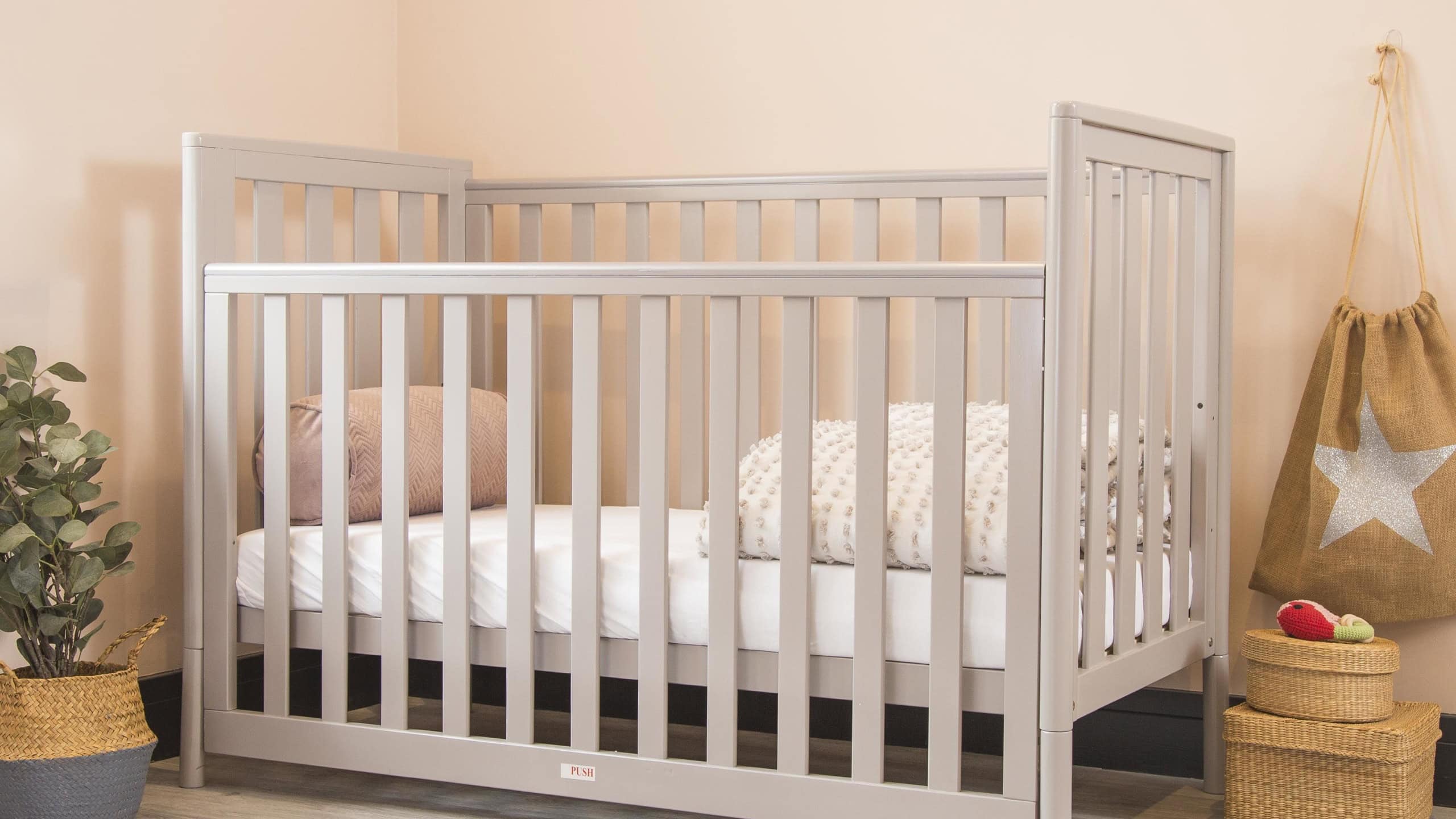 A modern baby room interior with a cozy classic crib with some decorative accessories on sides