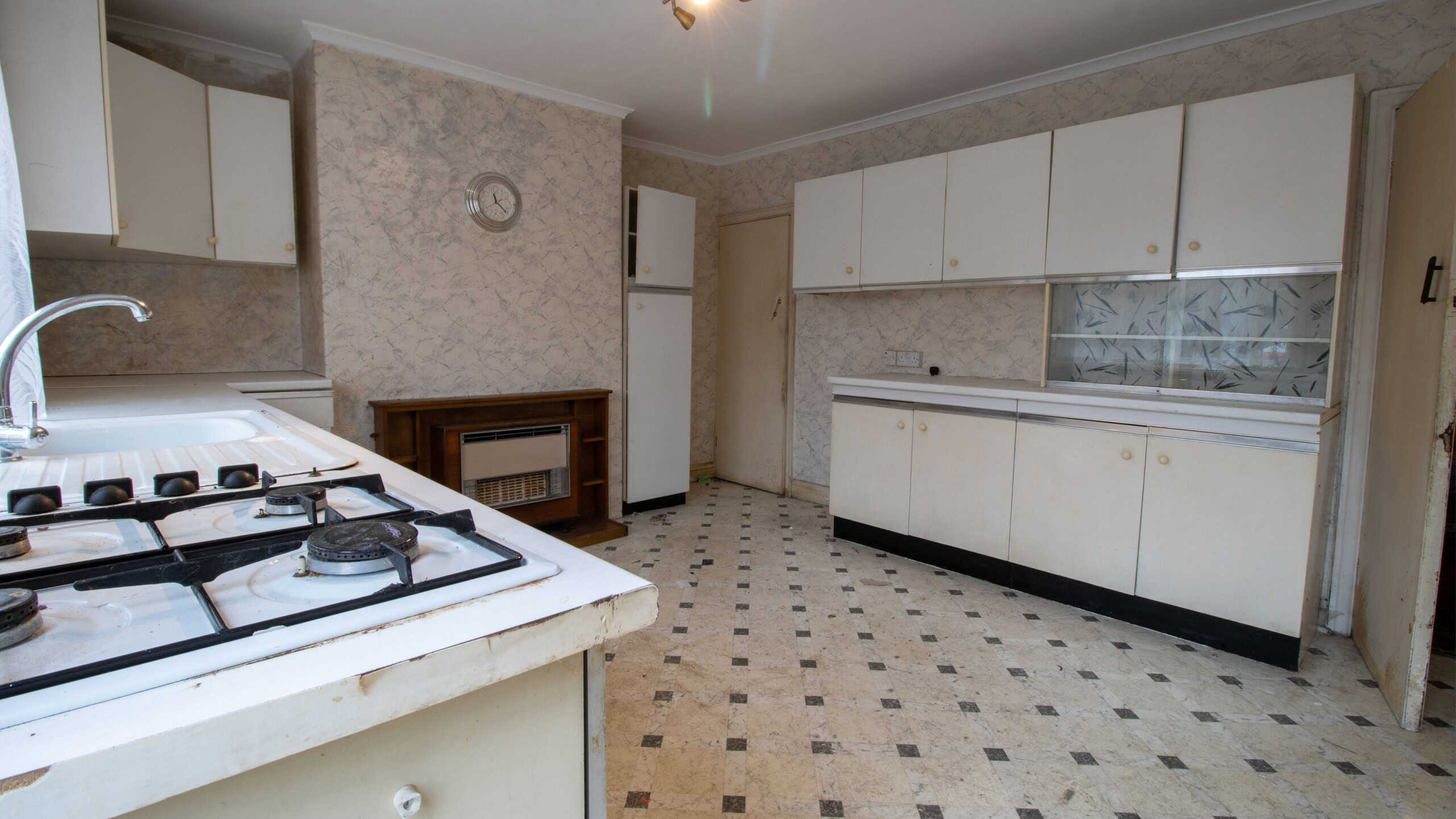 An old 80's style interior kitchen showing the run down kitchen in need of renovating with wooden kitchen cupboards.