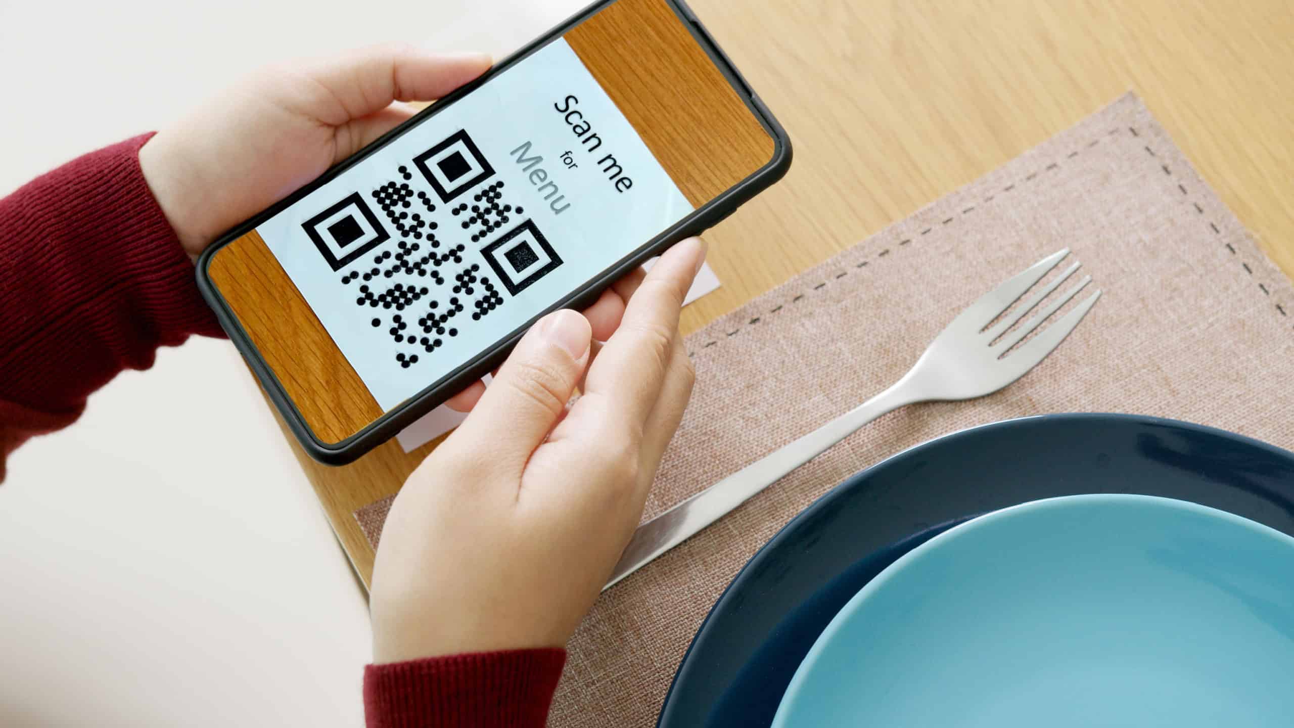 Hand's customer scan QR code for online menu service at table in restaurant during pandemic coronavirus. New normal contactless technology lifestyle protection coronavirus pandemic in restaurant