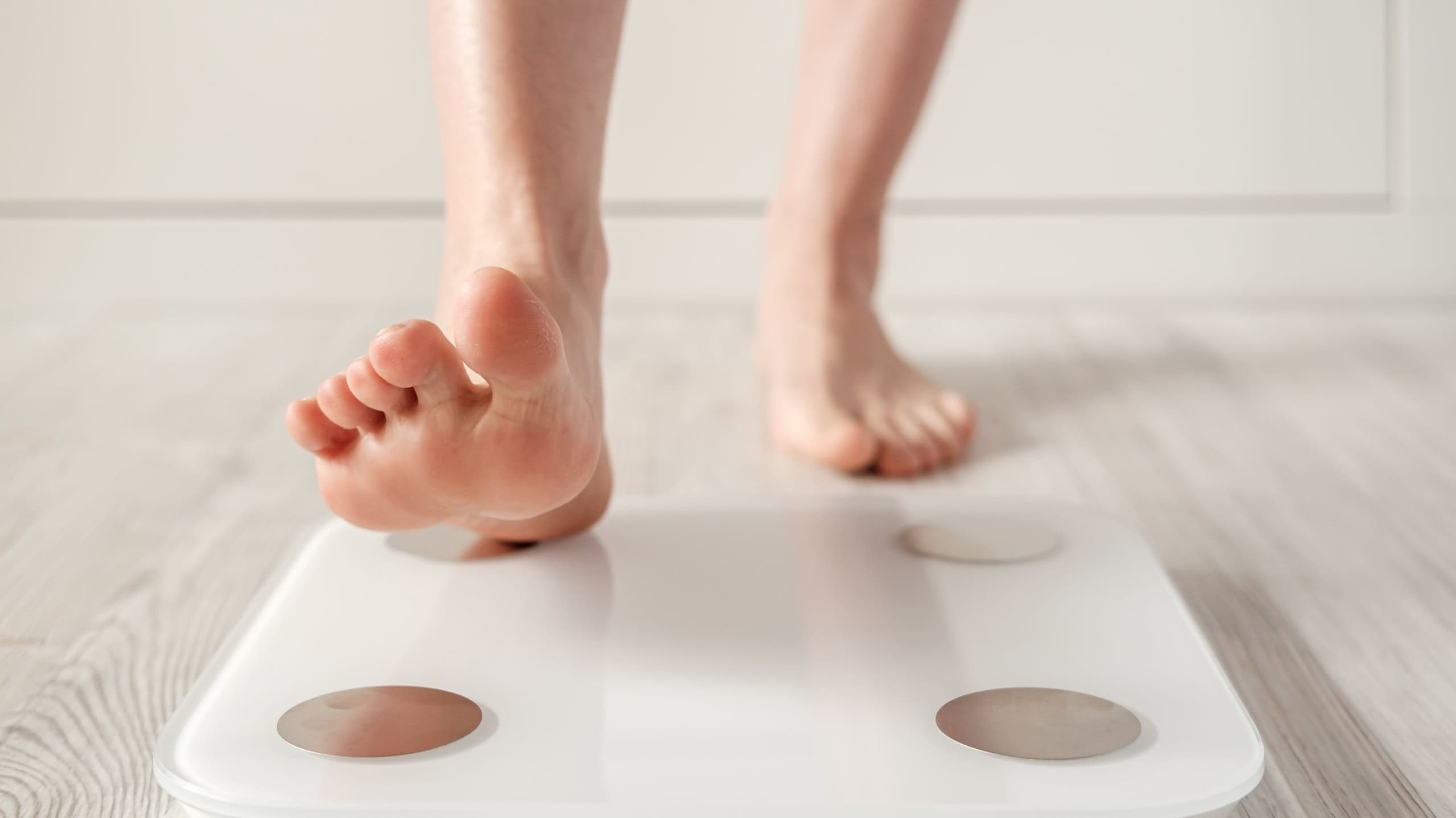 Woman foot takes a step onto a smart scale that makes bioelectric impedance analysis, BIA, body fat measurements.