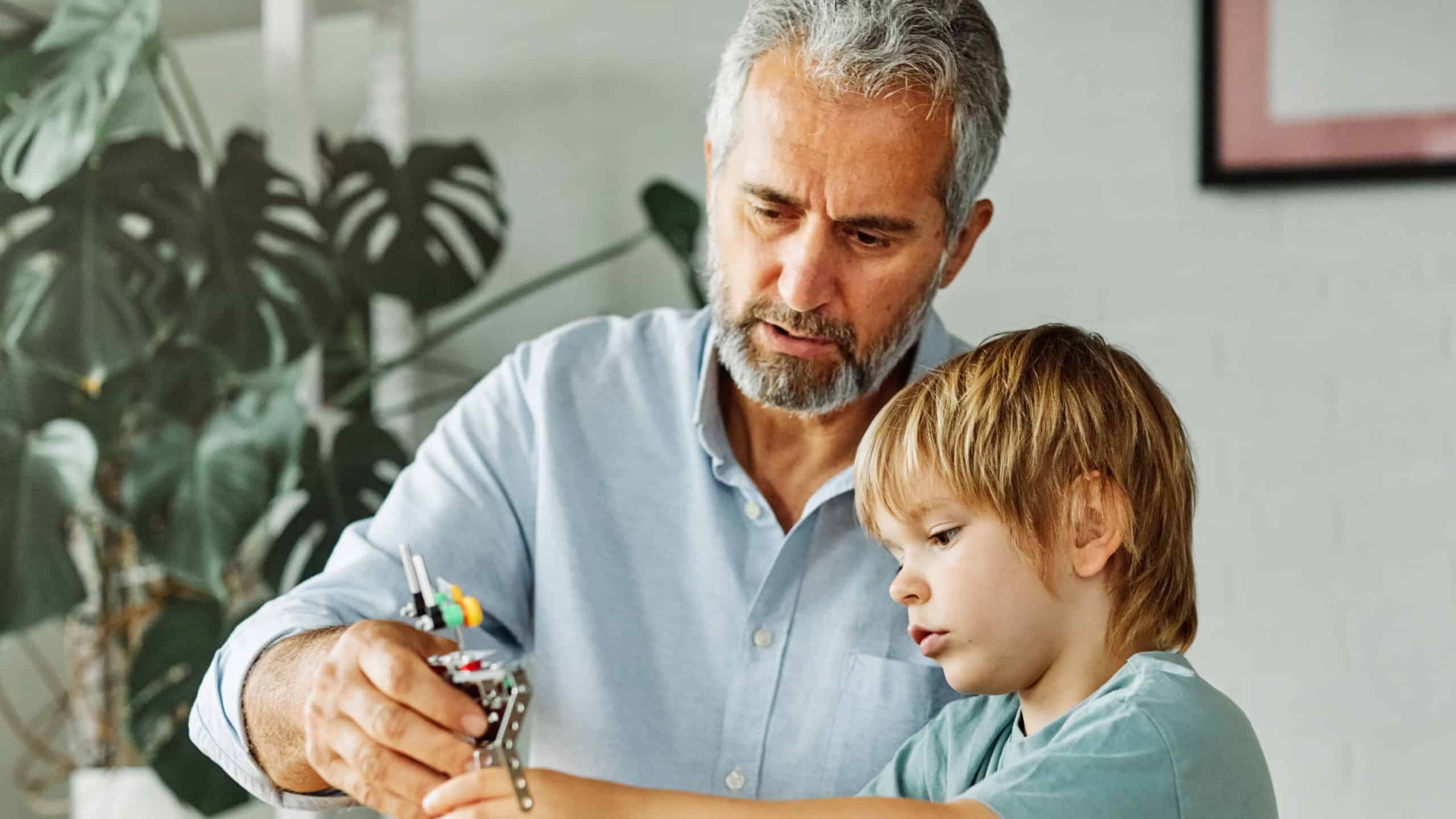 Portrait of grandfather and grandson having fun together building a toy robot at home