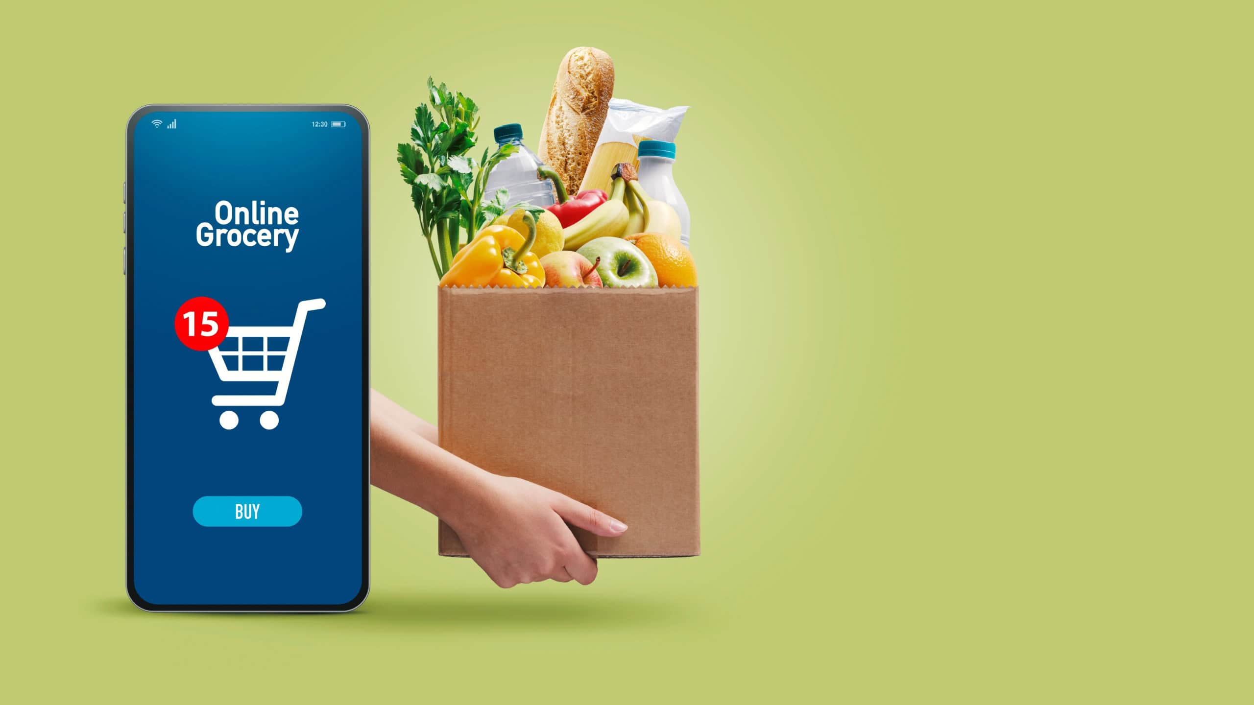 Hands holding a box full of fresh groceries and online grocery shopping app on smartphone