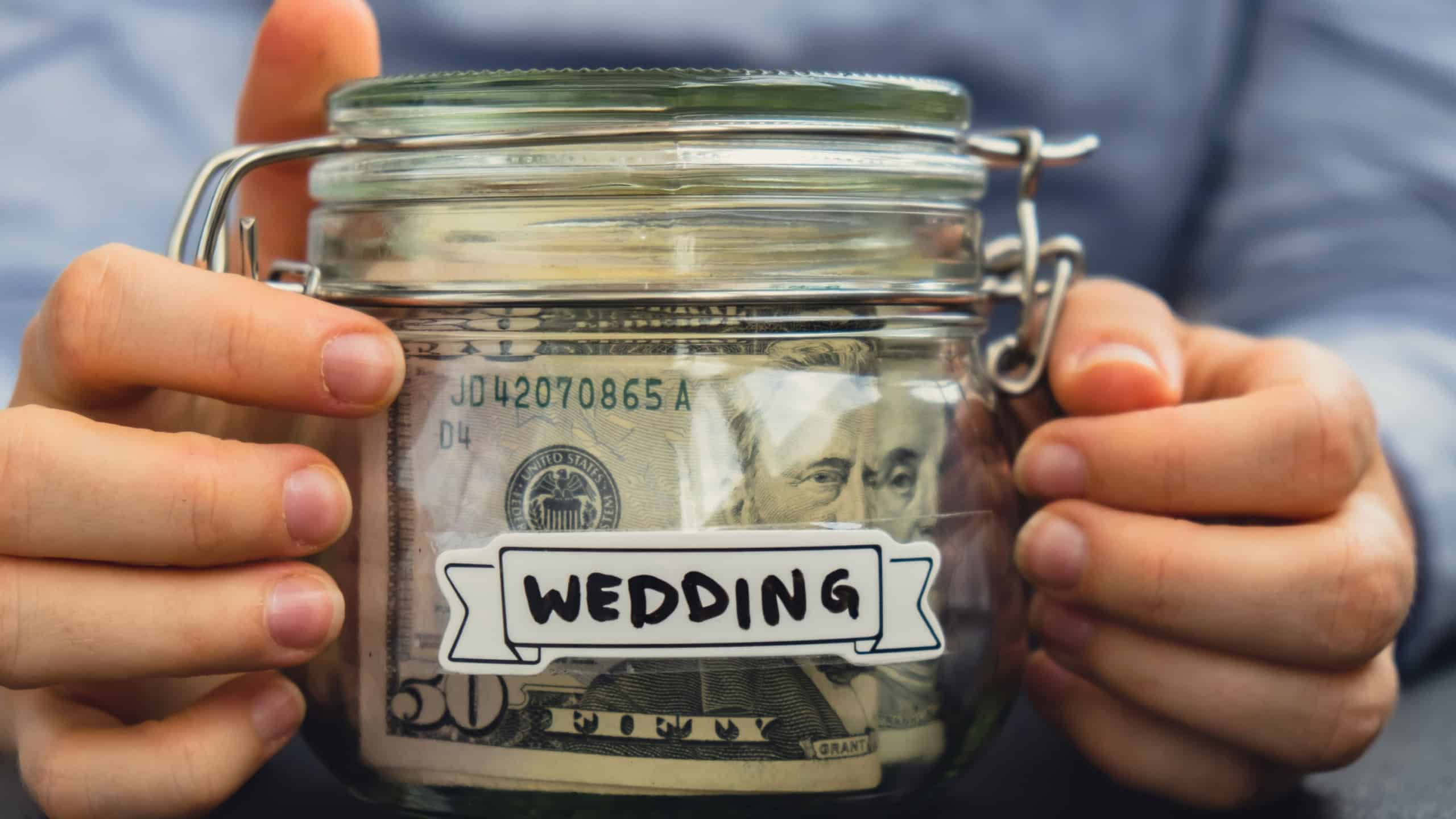 Female hands holding Glass jar full of American currency dollars cash banknote with text WEEDING. Preparation saving money. Moderate consumption and economy